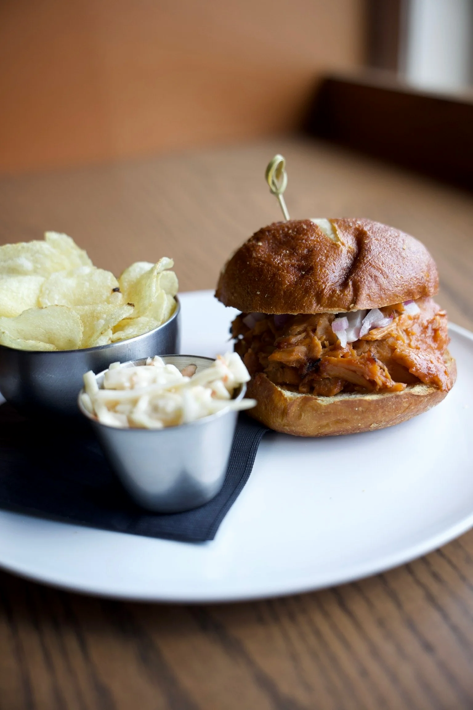  Pulled Pork Sandwich 
Slow - braised BBQ pulled pork topped with red onions, all stacked on a pretzel bun. Served with a side of coleslaw and kettle chips.