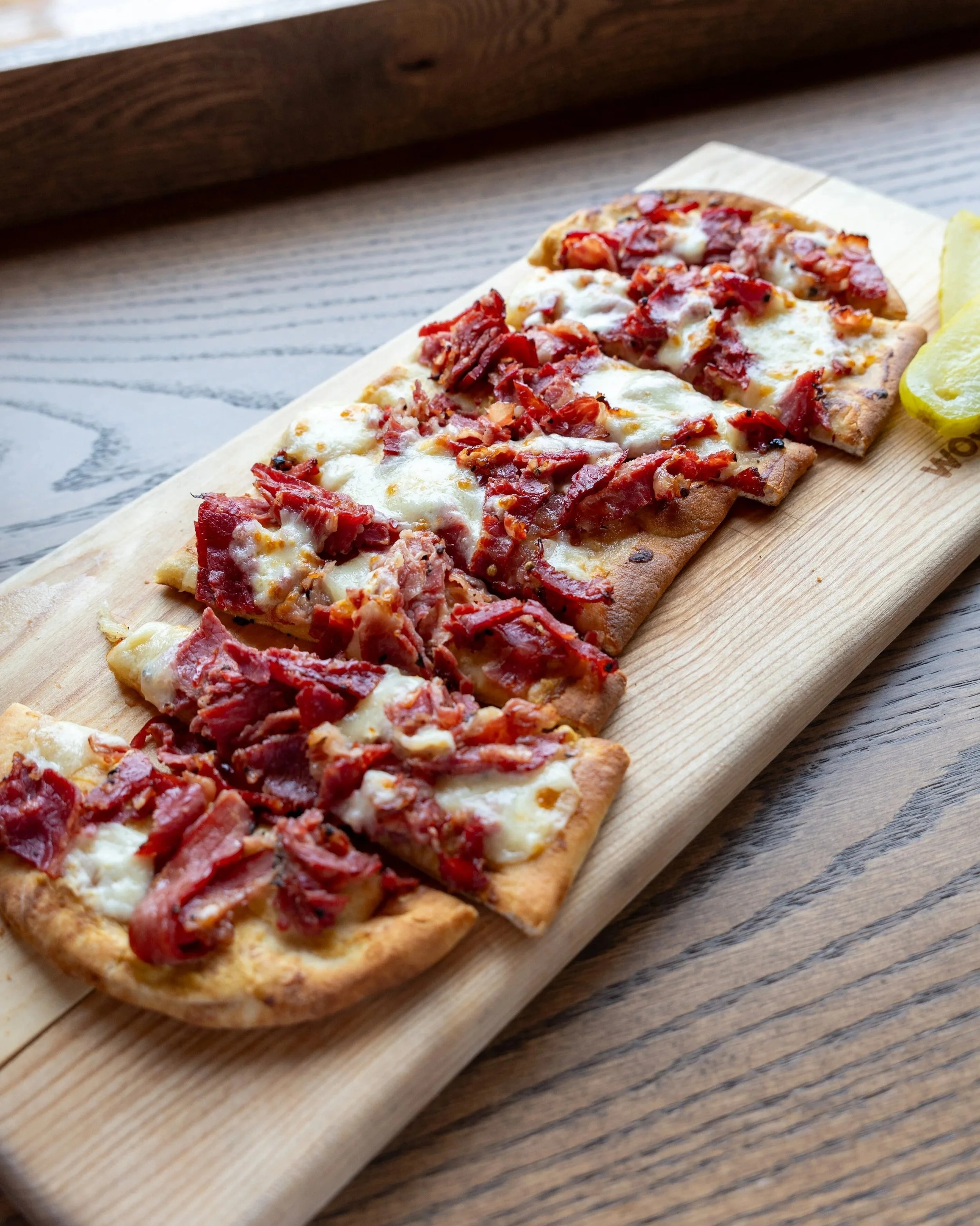  Great Canadian Flatbread 
Crispy flatbread topped with Montreal smoked meat, cheese curds, pickles, and dijon mustard.