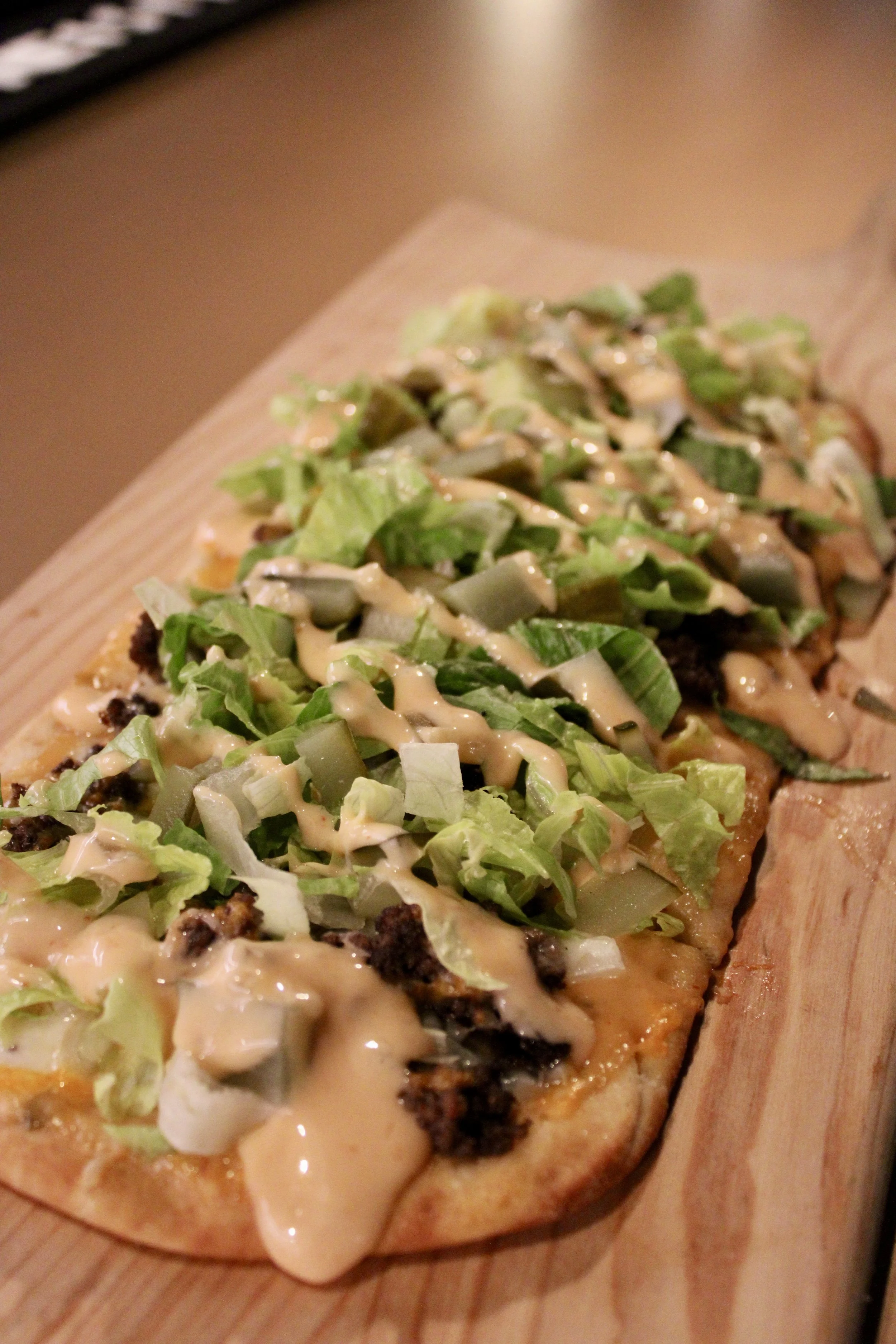  Mac Flat 
Seasoned ground beef, cheese, white onions, pickles and shredded lettuce on a
crispy flatbread. Finished with a drizzle of Thousand Island Dressing. 