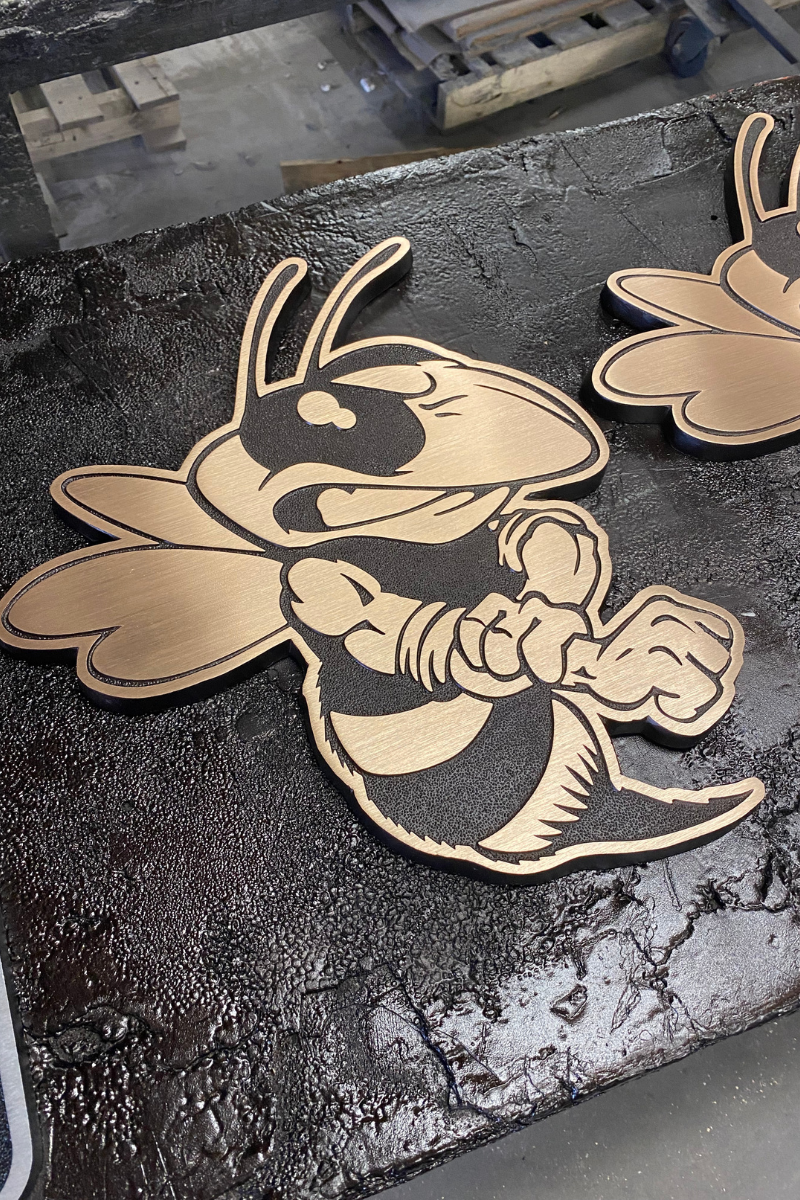 Custom gold-tone metal mascot signage featuring a detailed hornet design, showcasing precision craftsmanship for branded architectural signage by A.R.K. Ramos.