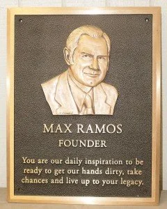 Close-up of a brass plaque commemorating Max Ramos, founder of A.R.K. Ramos, featuring engraved text and polished finish