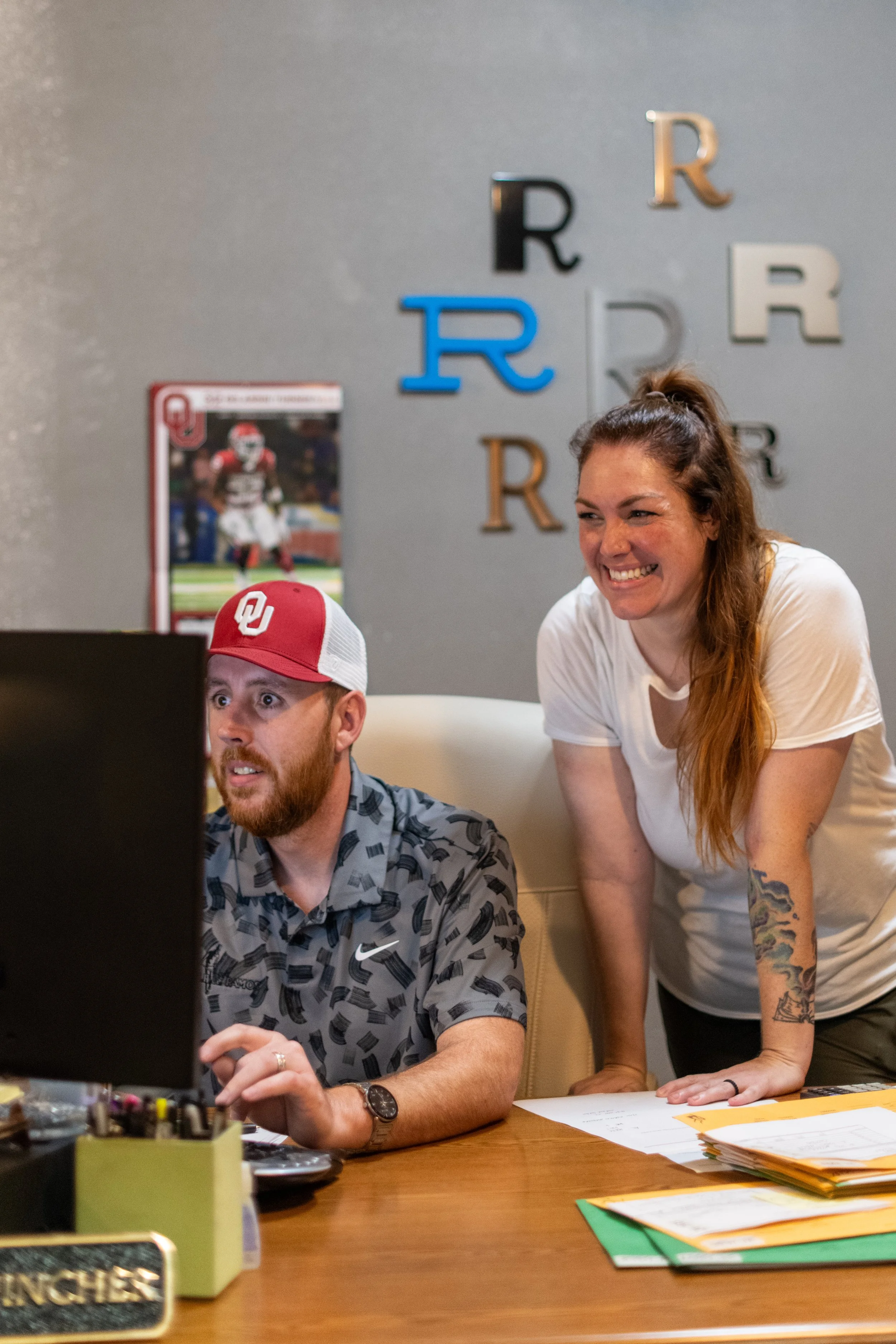 A.R.K. Ramos team members collaborating in the office with signage samples on the wall.