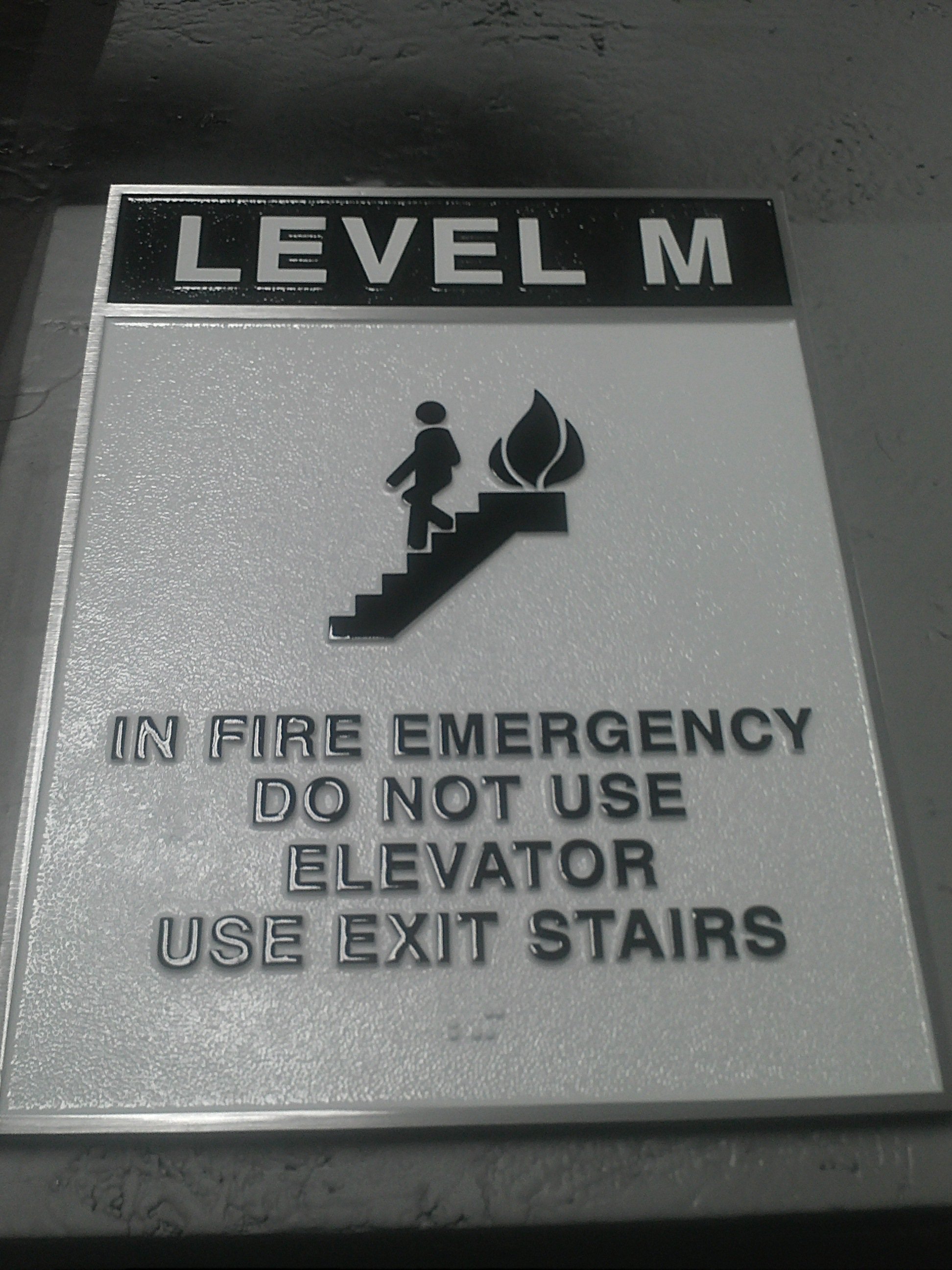 ADA signage displaying emergency exit stair instructions and fire safety guidance as part of an architectural signage and custom safety signs system.