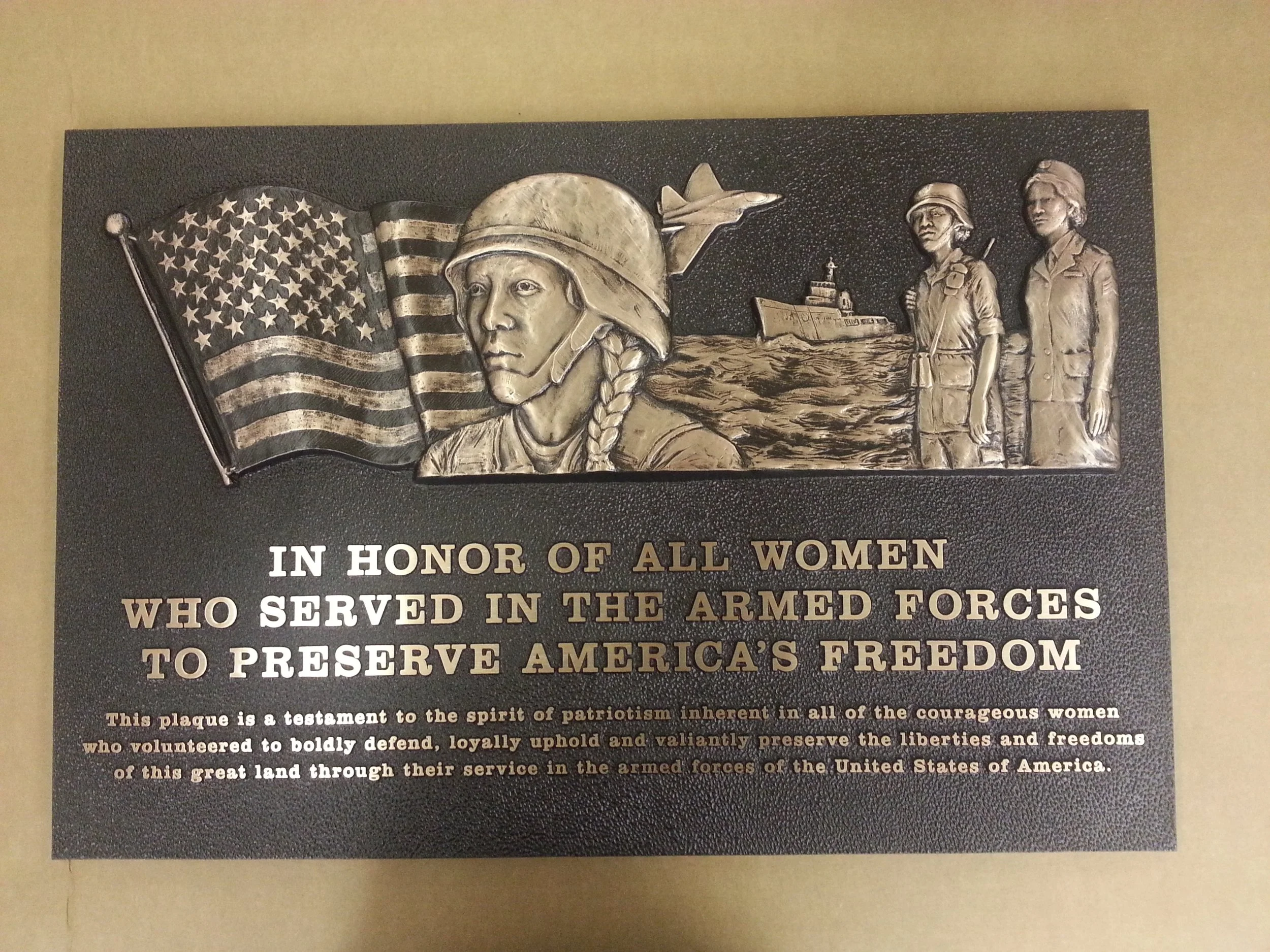 Bronze cast plaque honoring women in the armed forces with detailed reliefs and bold text.