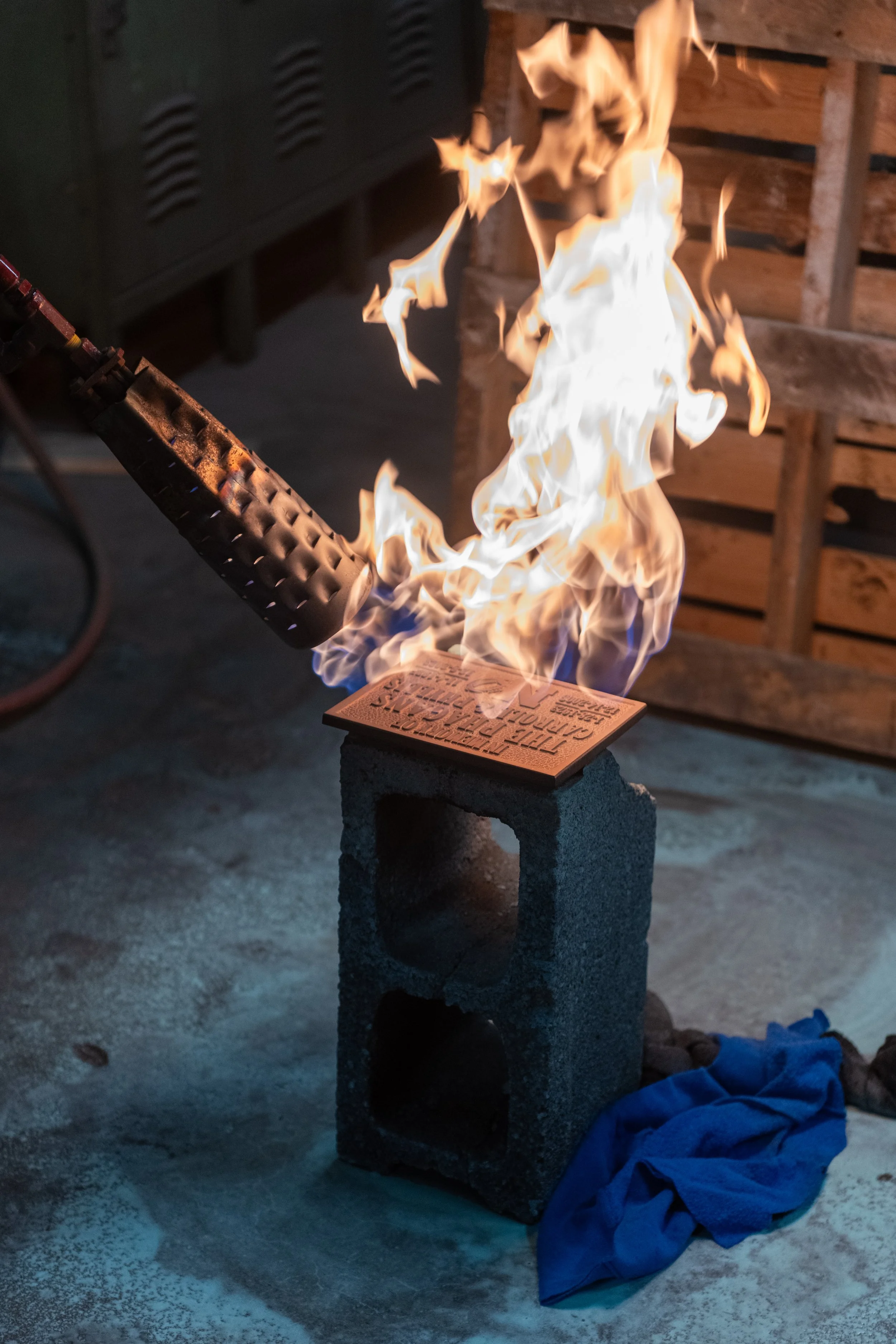 Flame finishing a cast metal plaque at A.R.K. Ramos, part of the custom signs for business process.