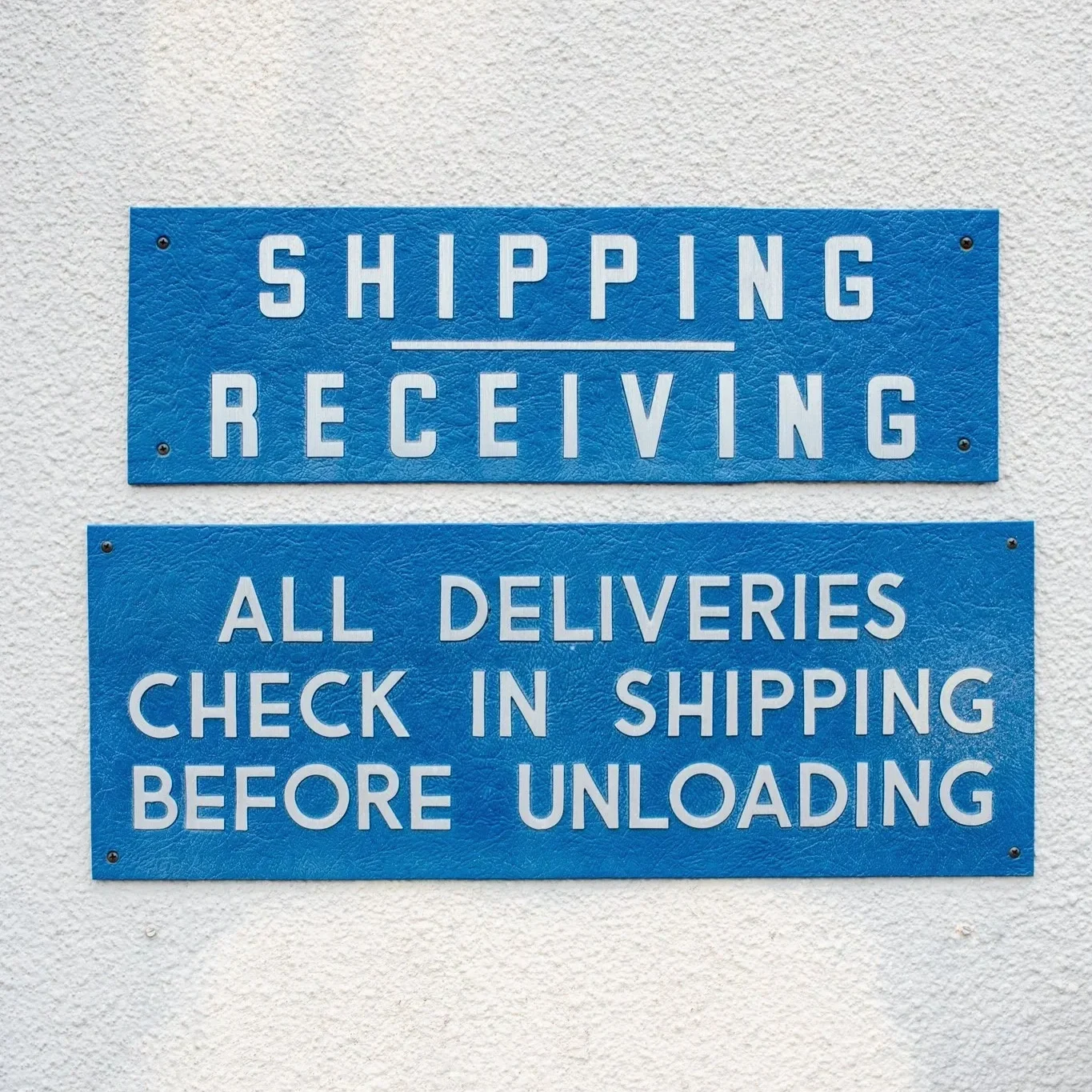 Blue cast plaque signs for shipping and receiving, showcasing the durable raised lettering and dimensional detail available for custom impression plaques and architectural signage.