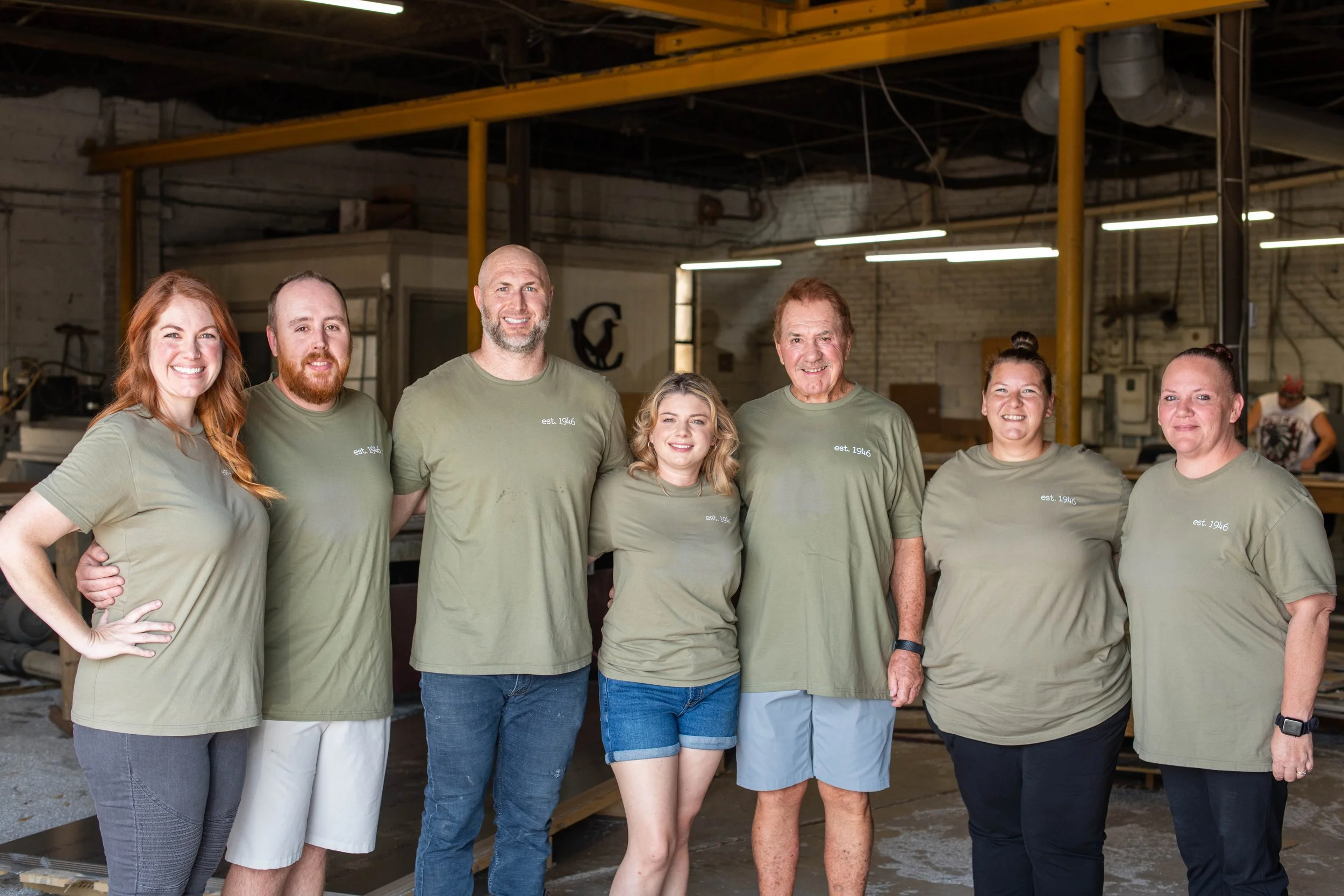 Team of craftsmen and staff in a workshop creating outdoor signage from durable metal, showcasing expertise behind long-lasting signage production