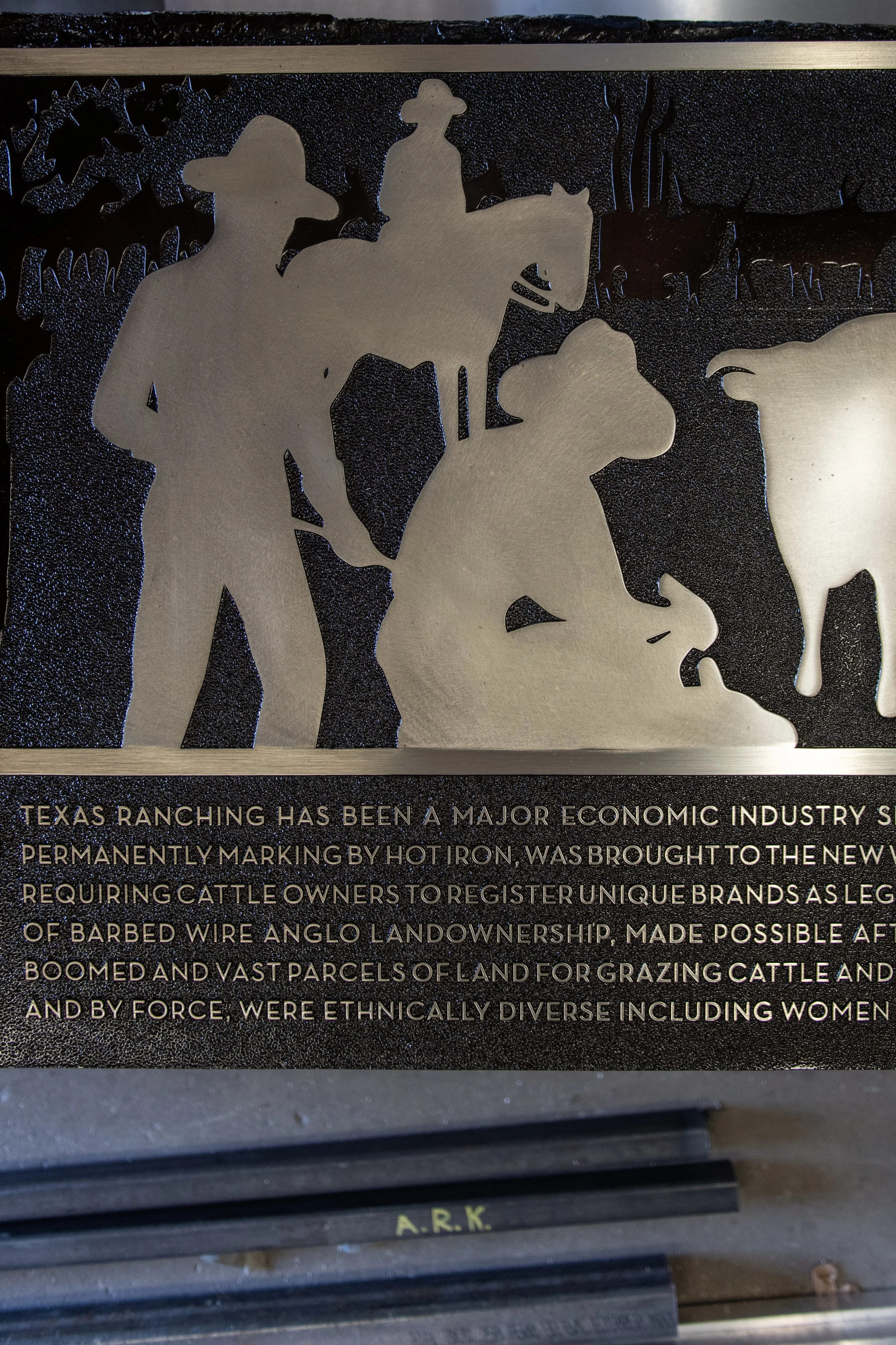 Etched and cast plaque depicting Texas ranching history, created by A.R.K. Ramos as a custom sign for business or institutional display.