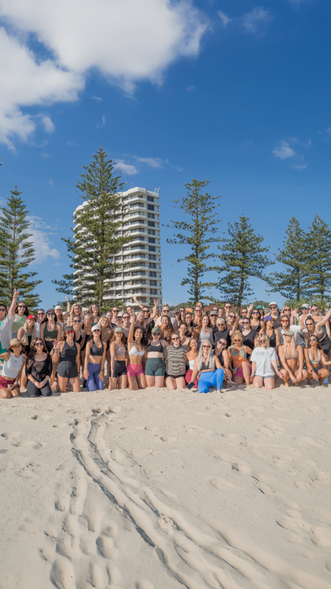 Large group of women gathered on the beach at a Sisterhood Movement community event at Burleigh Beach, on the Gold Coast