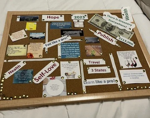 A bulletin board with motivational quotes, holiday messages, and photos, decorated with gold and silver pins, organized into sections about health, hope, self-love, travel, and wealth.