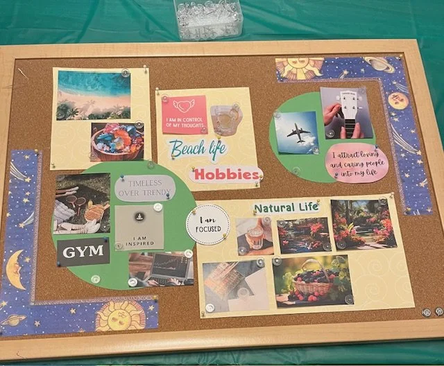 A corkboard with various photos, papers, and notes about hobbies, beach life, natural life, and fitness activities like gym. Visible items include a sunset photo, a bowl of colorful candies, an airplane, and outdoor scenery.