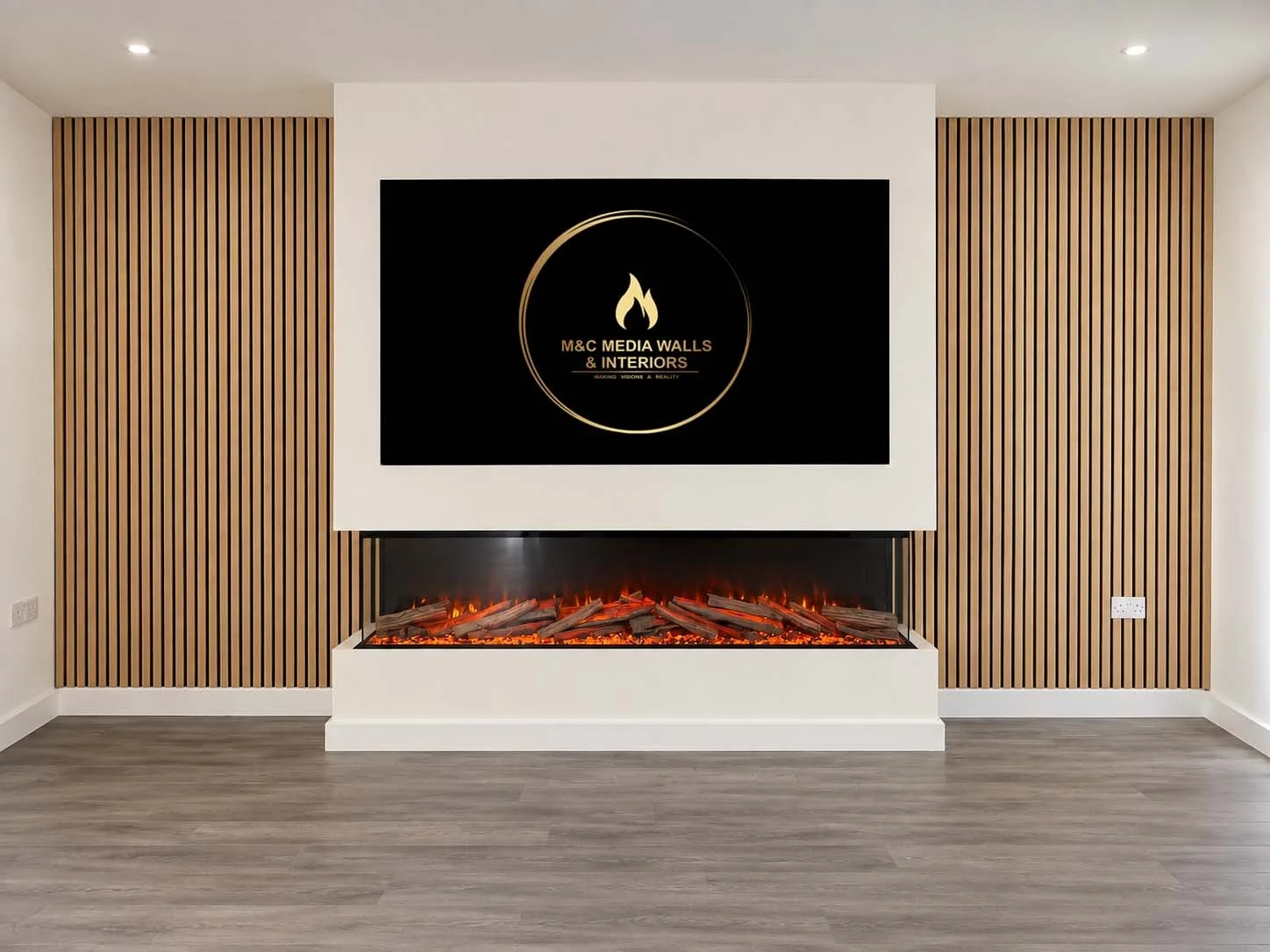 Modern living room with a wall-mounted electric fireplace beneath a large flat-screen TV displaying the logo for M&C Media Walls & Interiors, framed by wooden slat wall panels.
