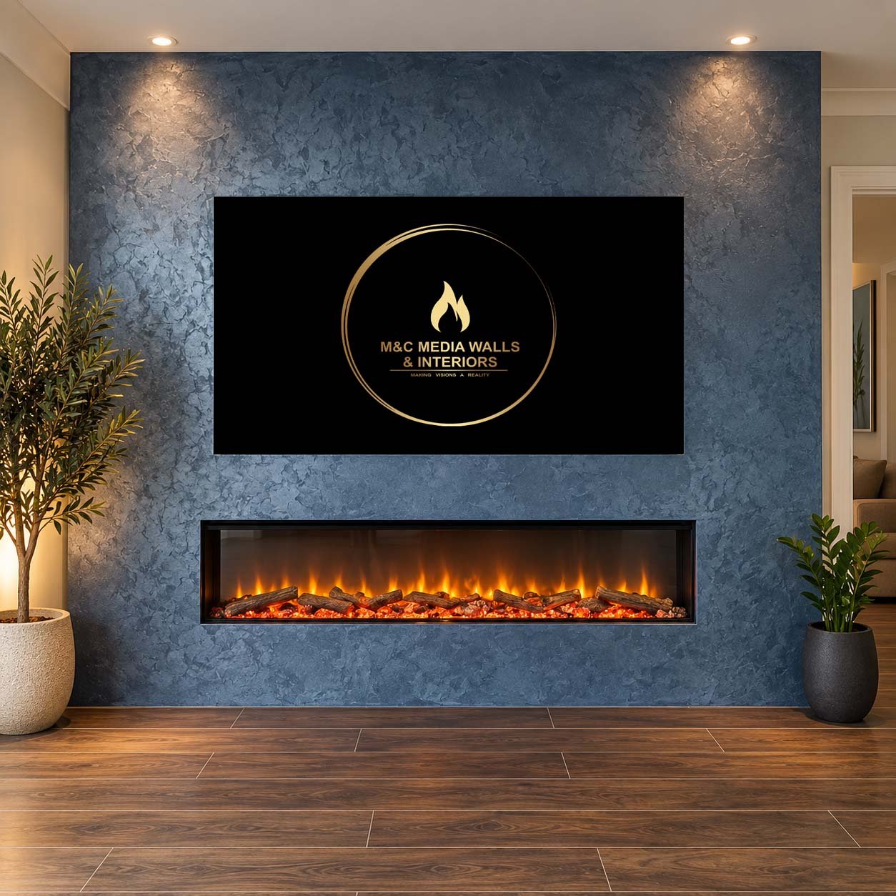 Living room with a blue textured accent wall, mounted television with a logo for M&C Media Walls & Interiors, modern fireplace below with glowing flames, wooden flooring, potted plants on the sides.