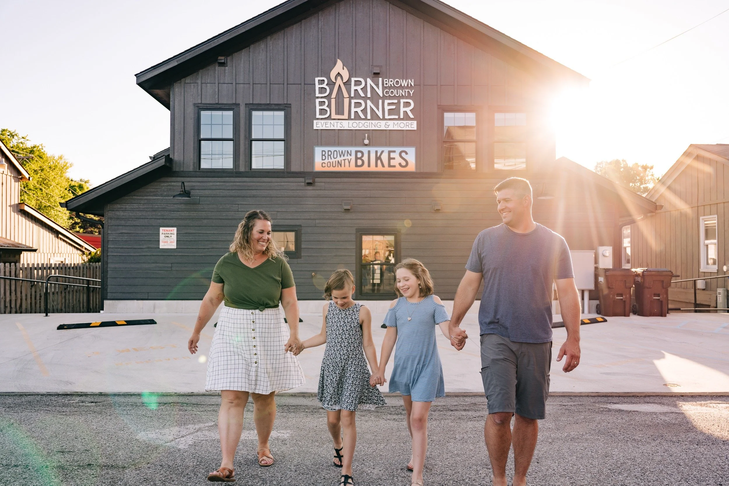 Family walking together outside a building labeled "Barn Burner Events, Lodging & More" and "Brown County Bikes," highlighting a welcoming option for where to host my retreat.