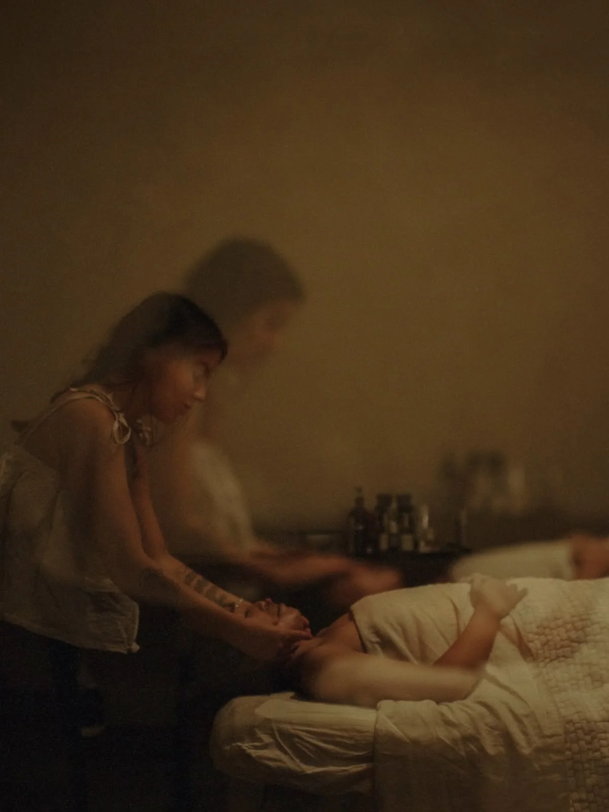 A woman receiving a massage from another woman in a dimly lit room.