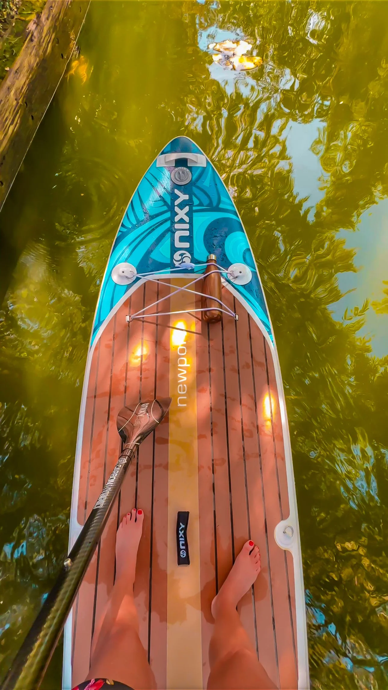 First-person view of paddleboarder’s feet on a NIXY paddle board during a Winter Park paddleboarding tour