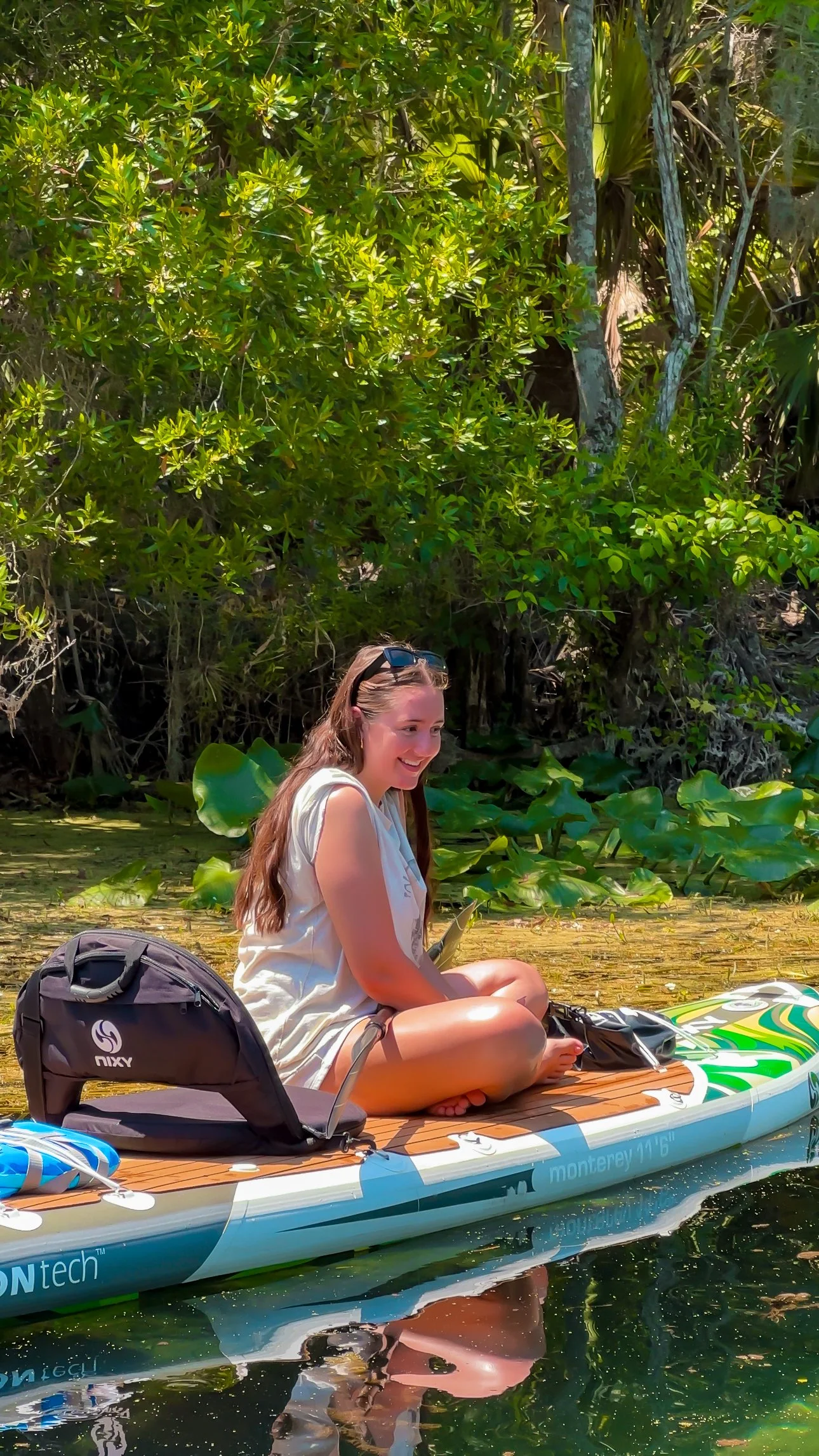 Guest smiling while paddleboarding on a kayak-style hybrid setup during a guided Winter Park paddle tour with Otter Paddle Orlando