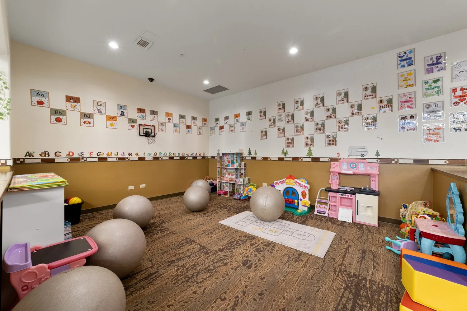 Children's playroom with toys, exercise balls, and colorful alphabet and number decorations on the walls.