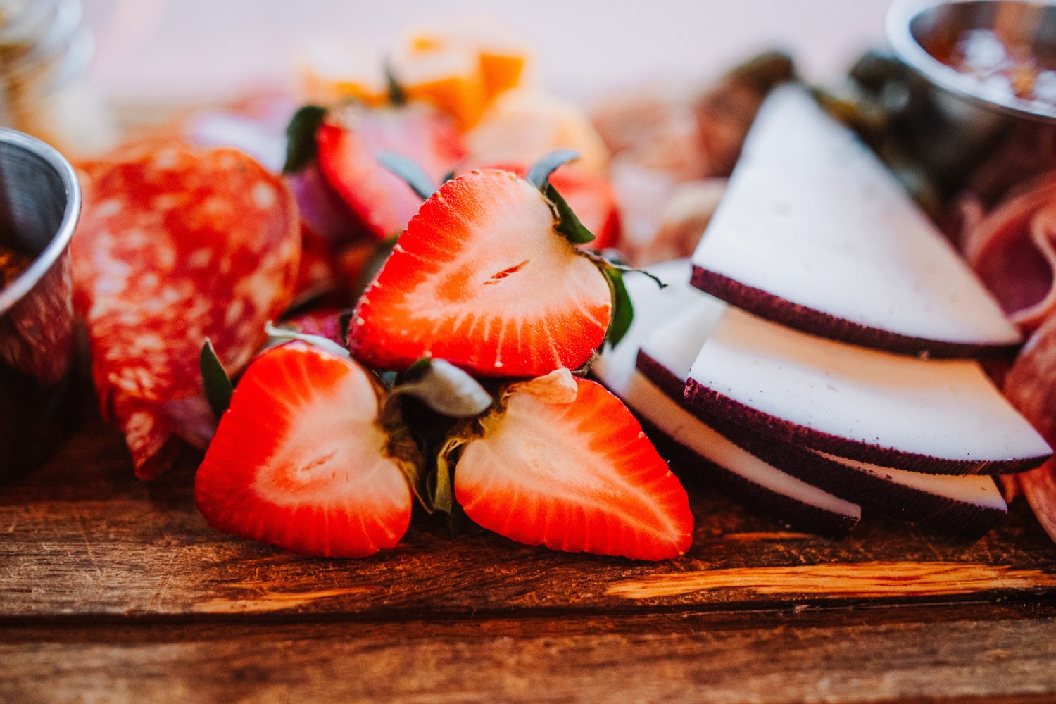 Sliced strawberries and layered cheese or dessert slices on a wooden surface.