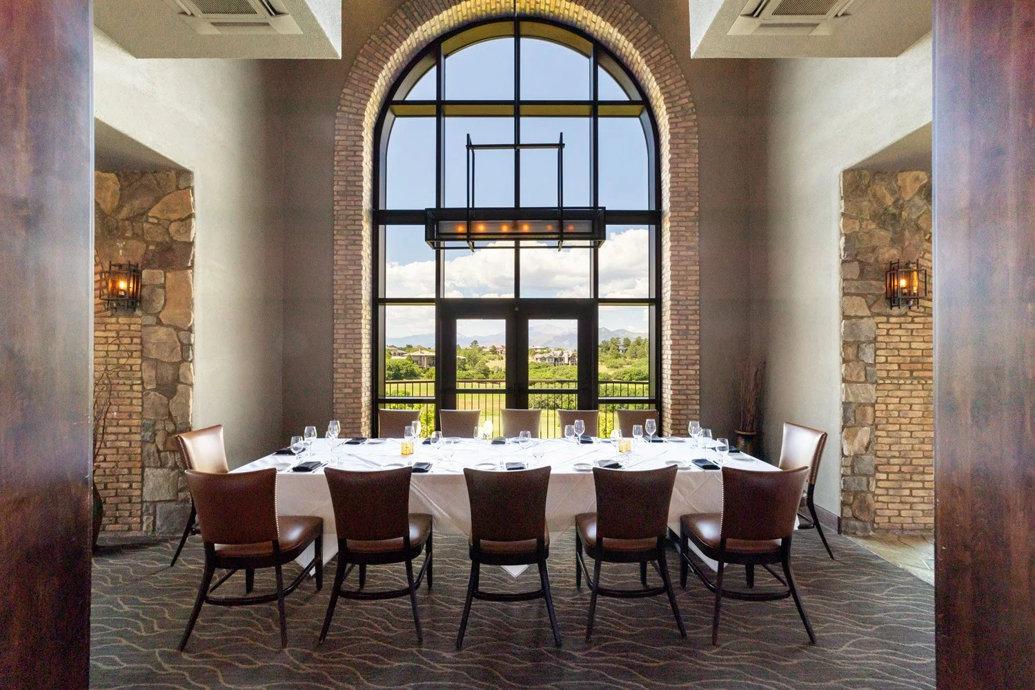 grand seating for 12 in front of large bay window with views of the golf course and rocky mountains