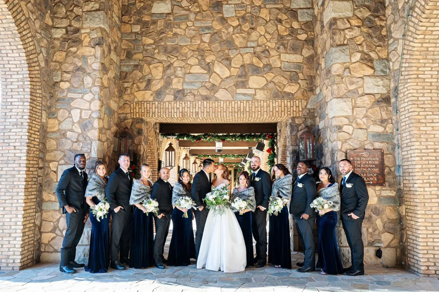 winter wedding party posed in front of the clubhouse brick entrance