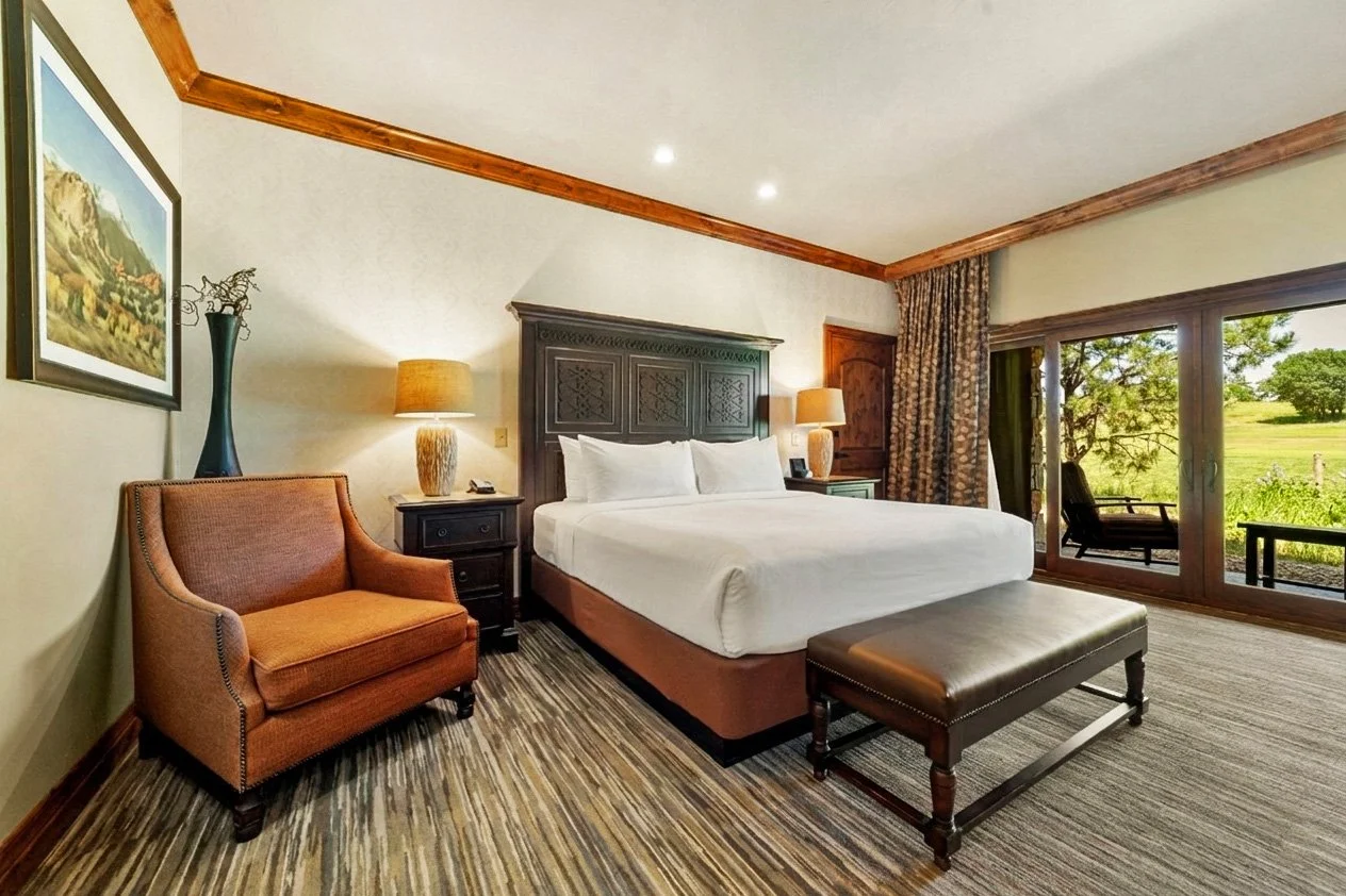 king bed with large chair and private patio with golf course view