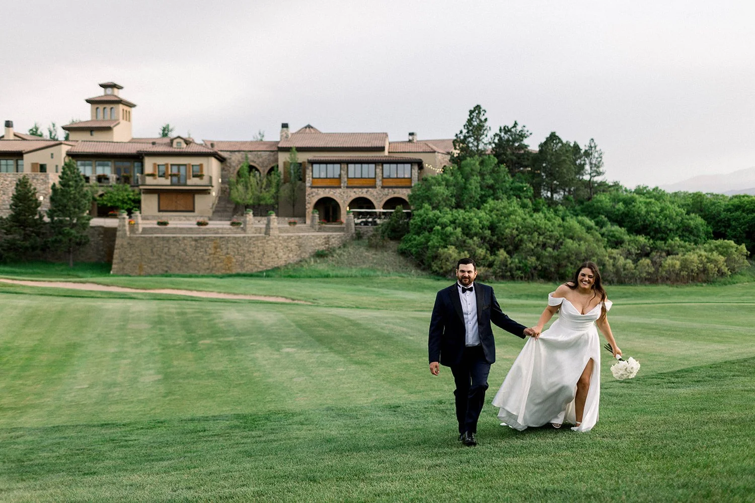 bride and group taking photos on golf course with clubhouse in the background