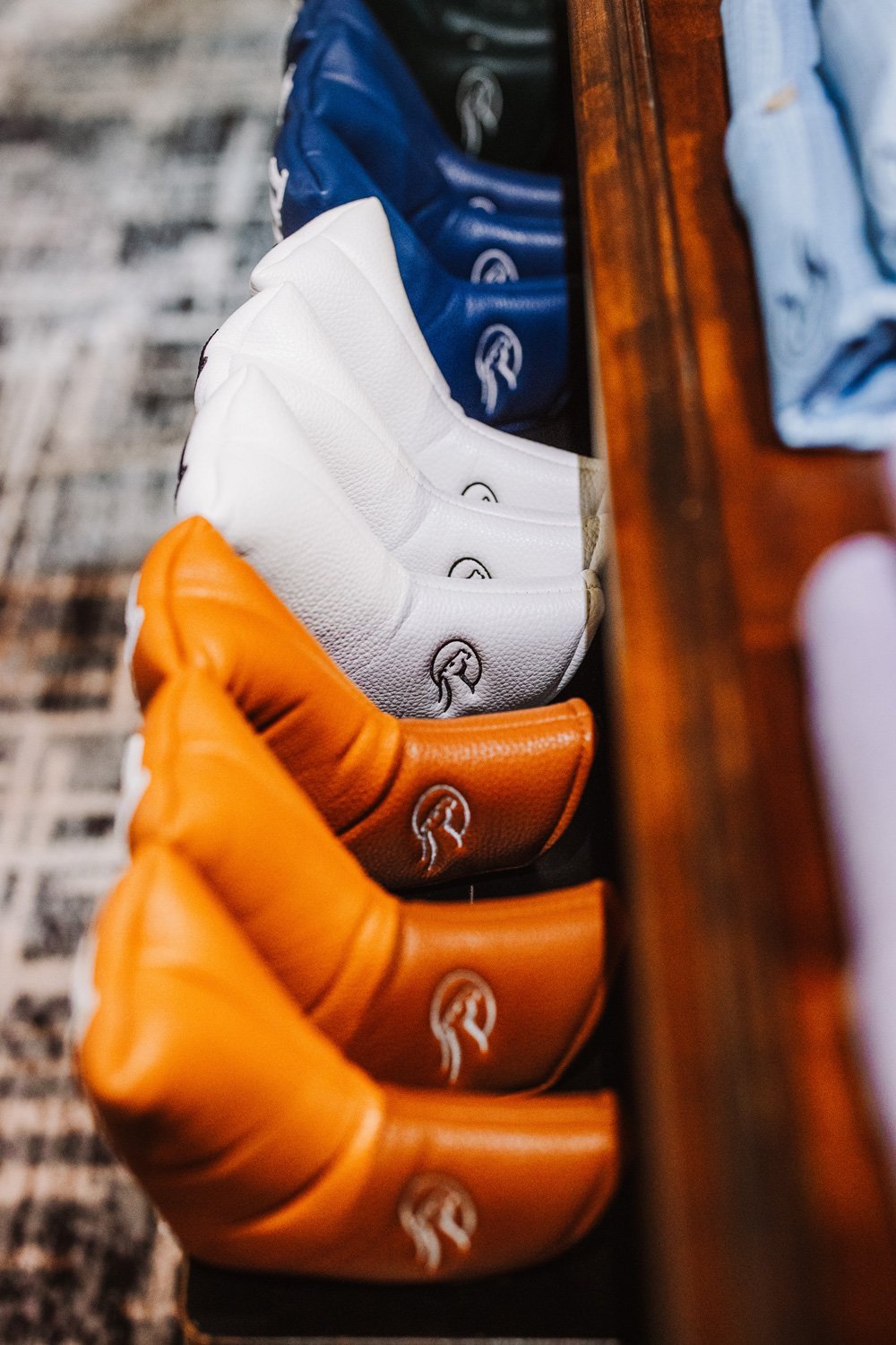 blue white and tan driver head covers in a line at the golf shop 