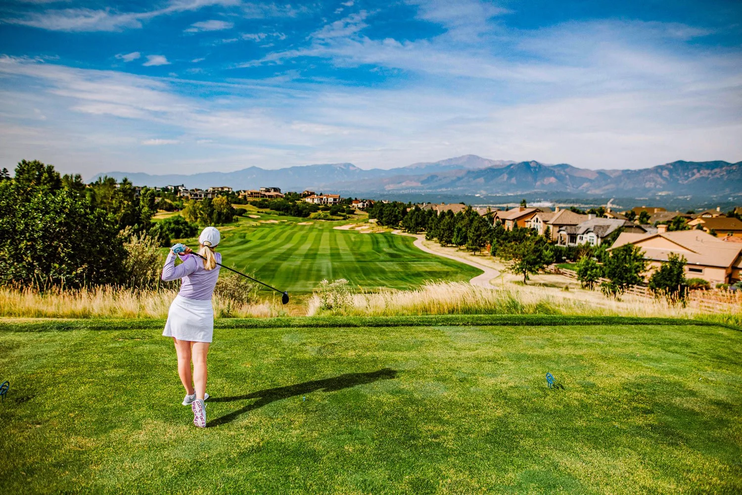 woman teeing of on golf course looking west at the mountains