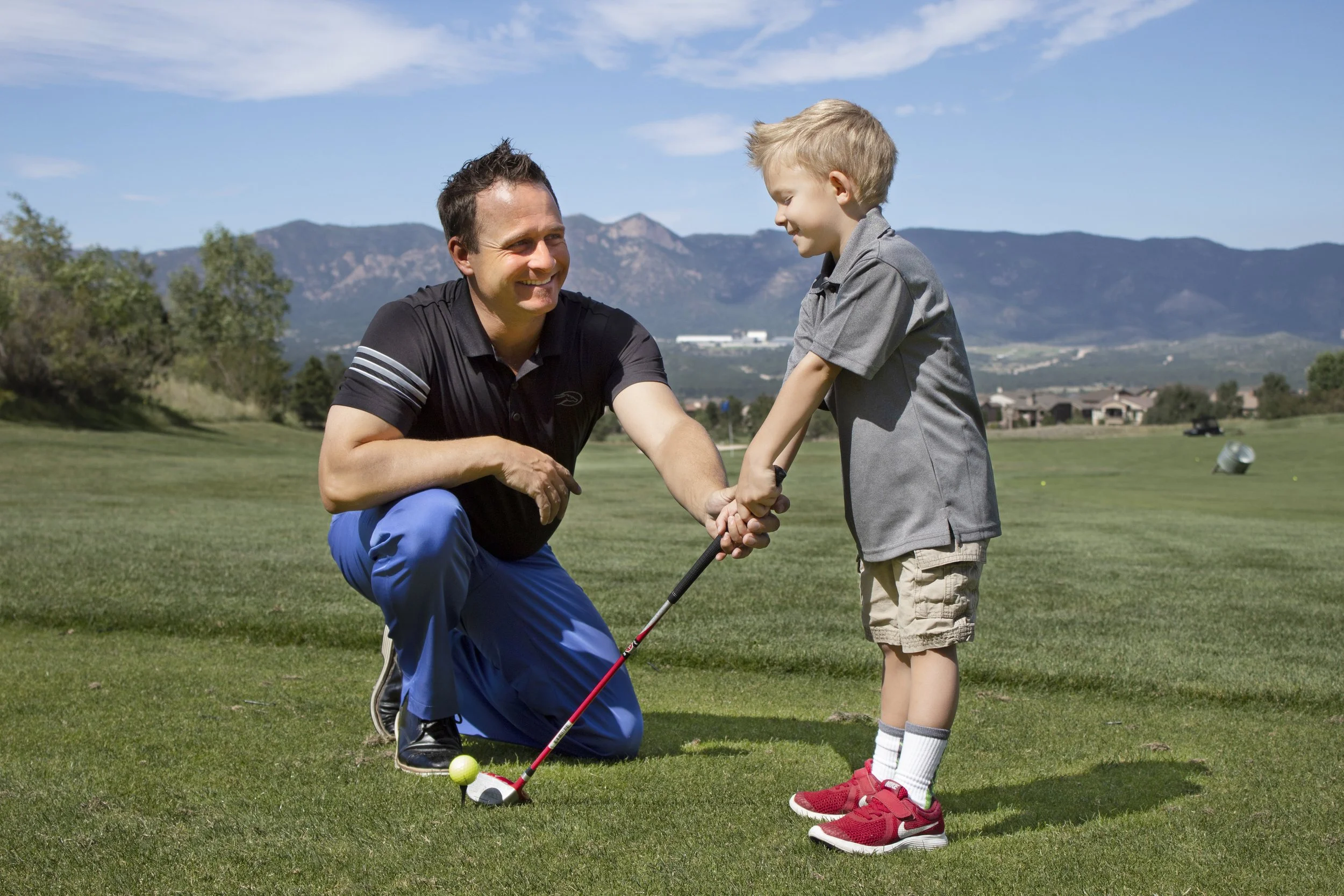 junior golf instructor helping a child hold a golf club