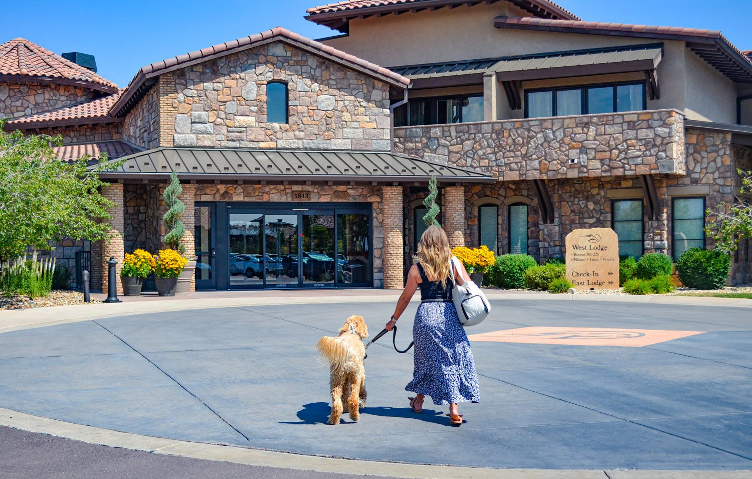 woman walking into the west lodge to check-in to hotel room with her dog