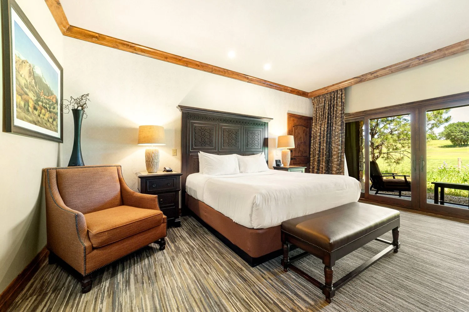 king bed with large chair and private patio with golf course view