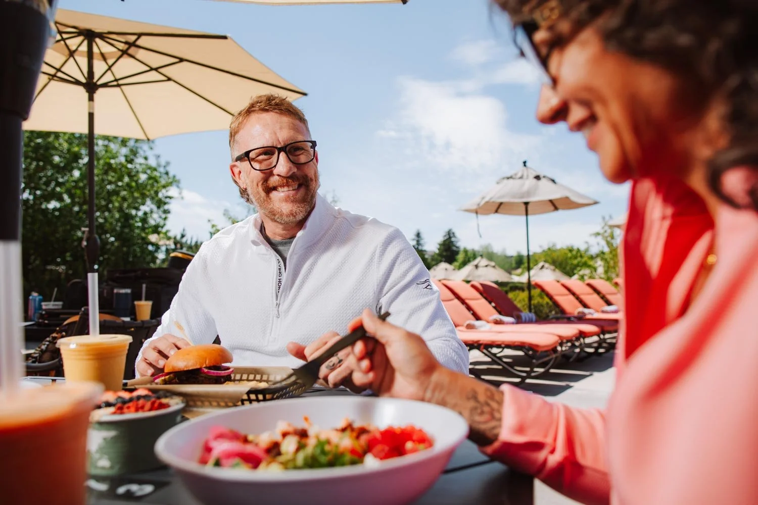 couple eating food from the athletic grill by the pool after a workout