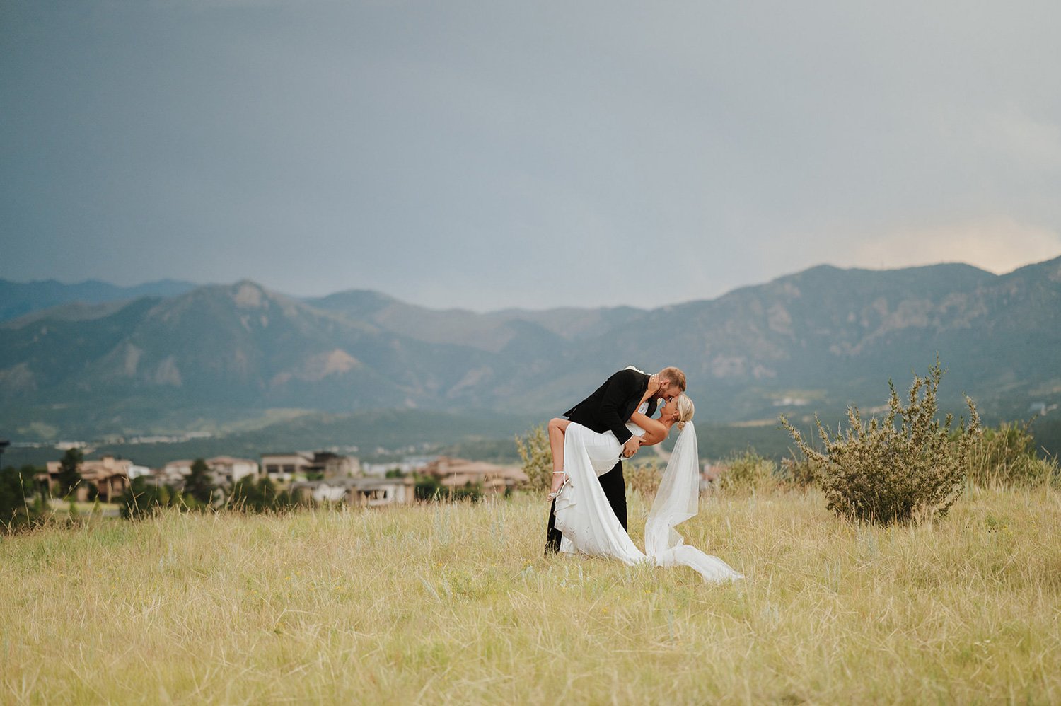 wedding couple kissing in front of the mountains on the golf course