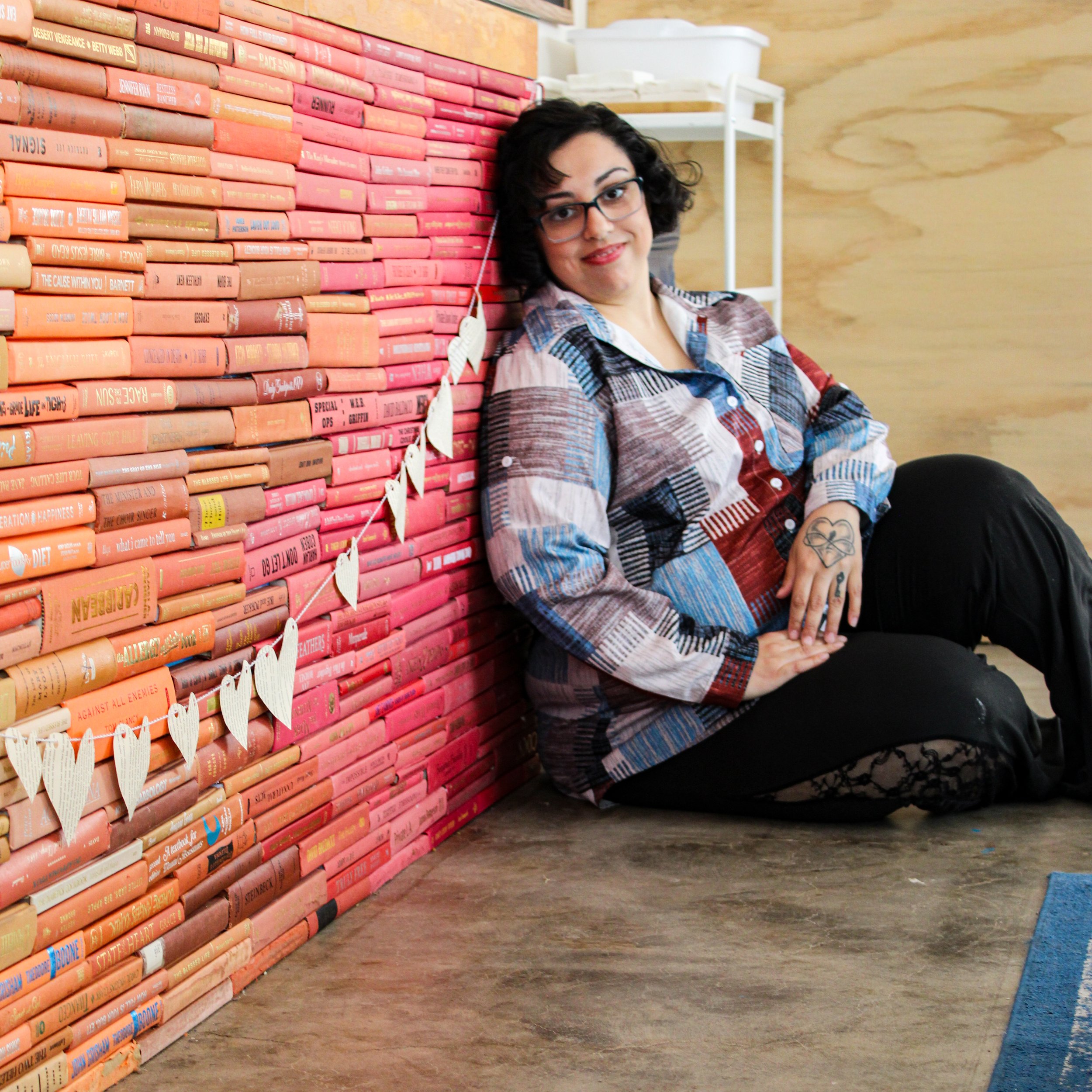Woman sitting against colored books