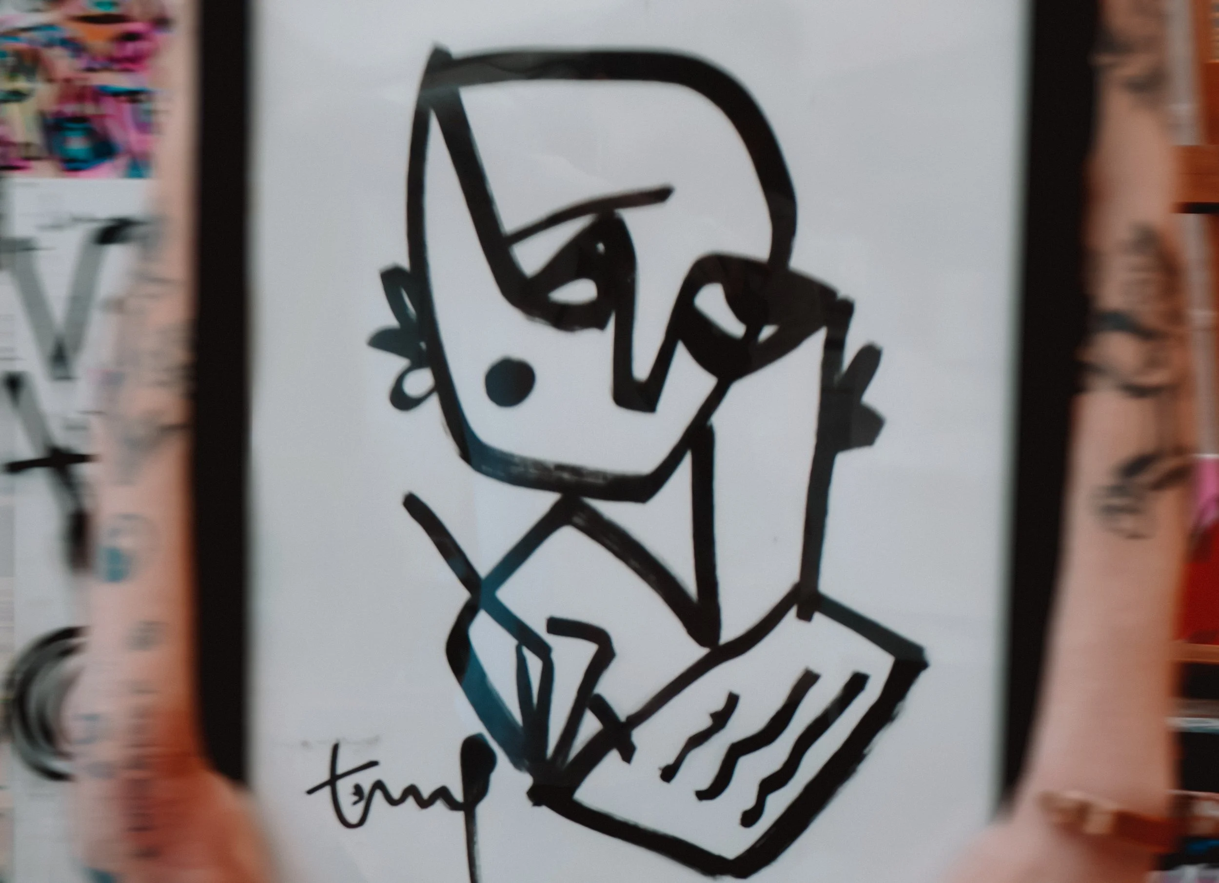Abstract black line drawing of a person's face with glasses, holding a phone to the ear, and a laptop in front, signed by the artist 'Tamp' at the bottom.