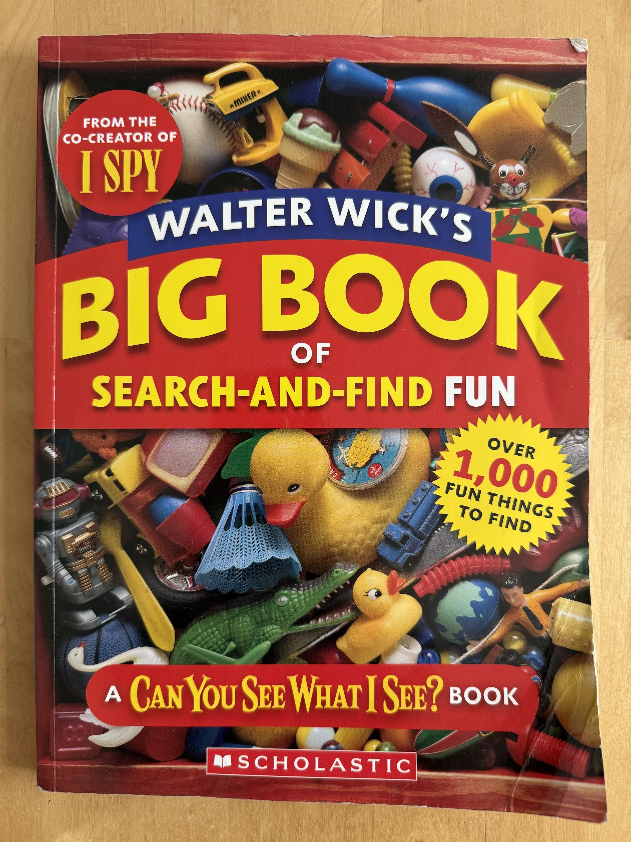 Cover of a children's book titled "Walter Wick's Big Book of Search-and-Find Fun" with various small toys and objects inside a clear box, including a rubber duck, a toy alligator, a plastic ice cream, a toy dragon, and other colorful items.
