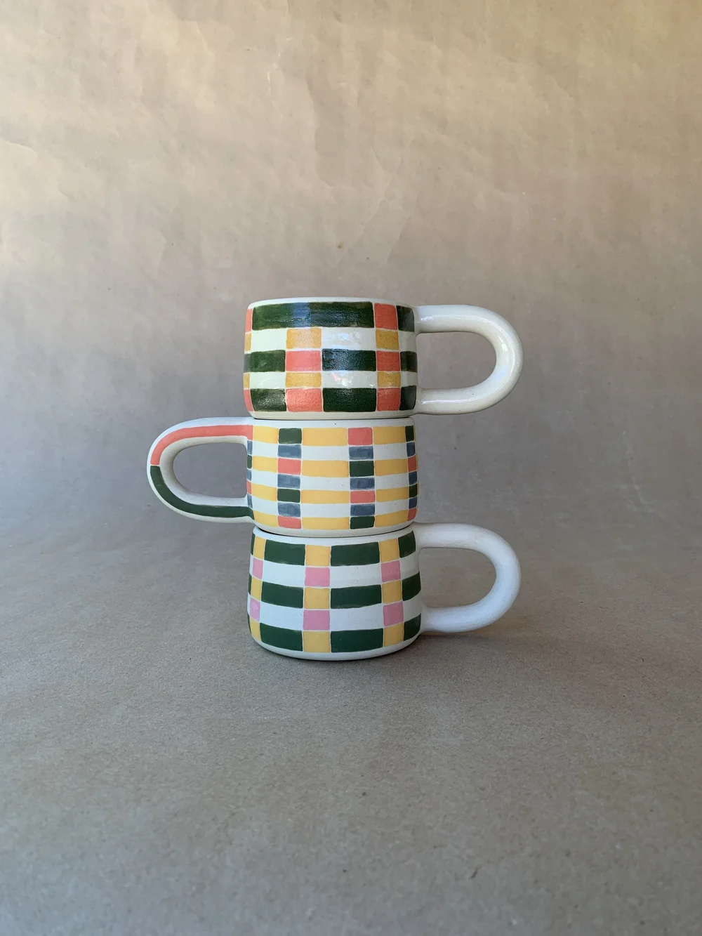 Two stacked handmade checkered ceramic mugs by Ware Ware Studio
