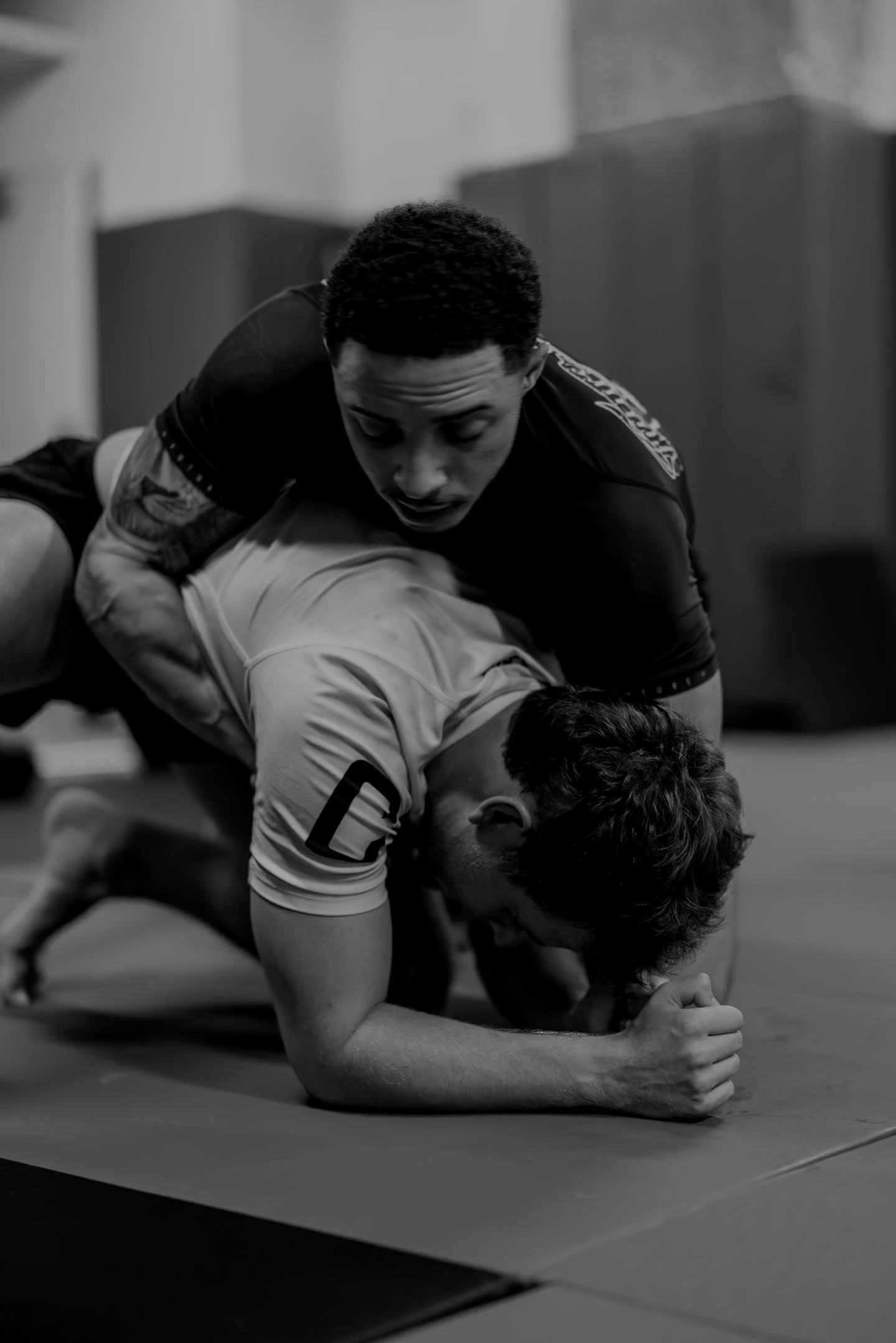 Two men grappling jiu jitsu on the mats