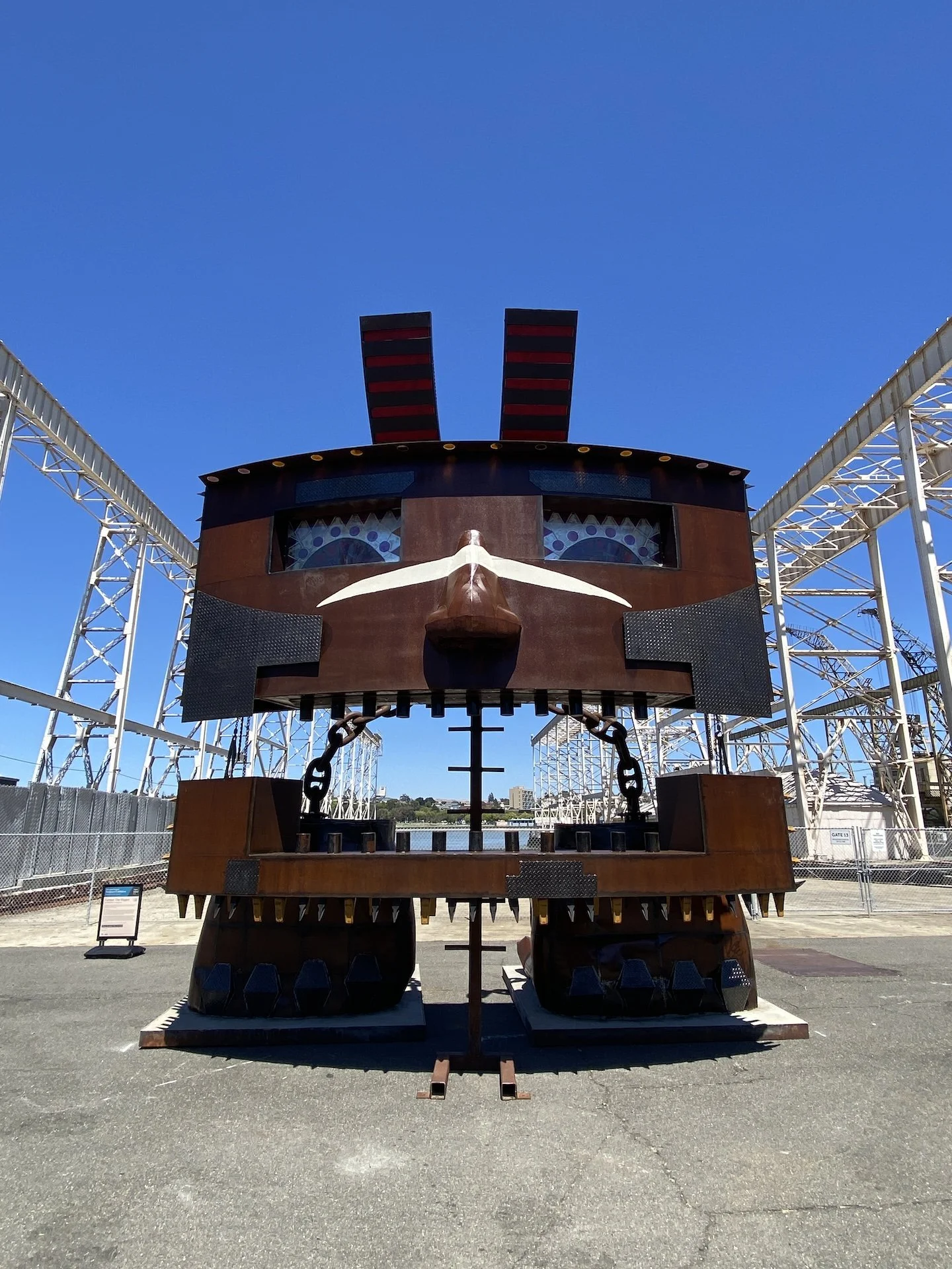 Large mechanical bull ride at an amusement park, with a clear blue sky and roller coaster tracks in the background.