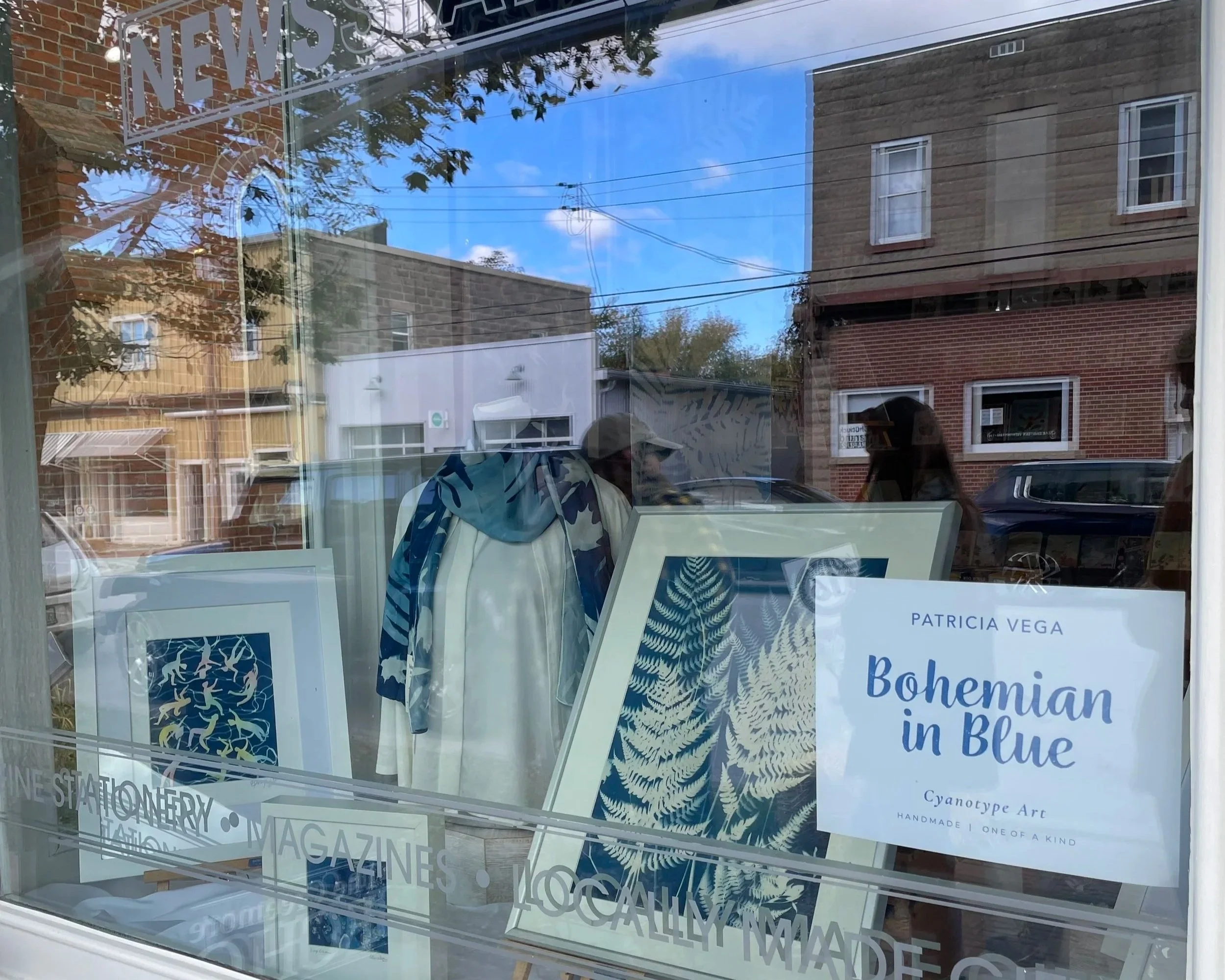 The Bohemian in Blue collection fills the Creemore storefront window with cyanotype scarves, prints, glass paperweights and framed artwork.