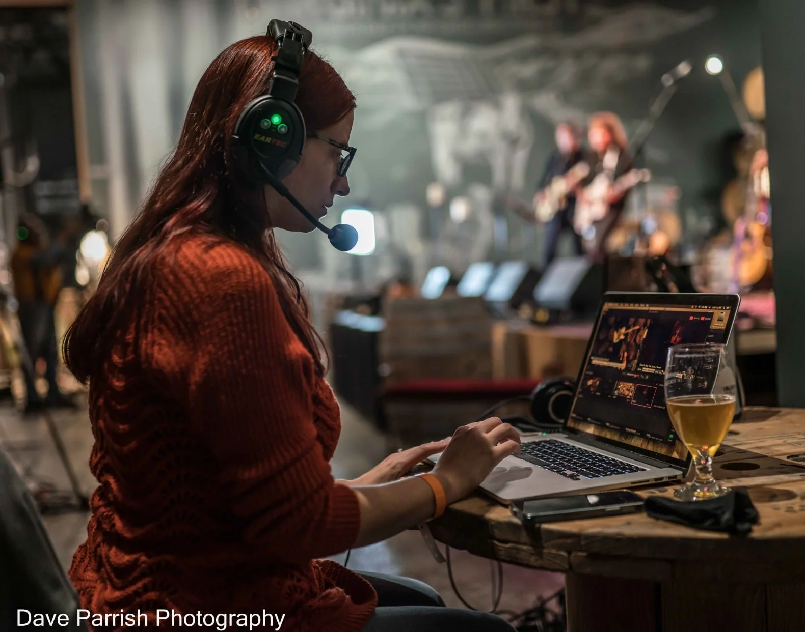 A woman with a microphone headset, working on a computer.