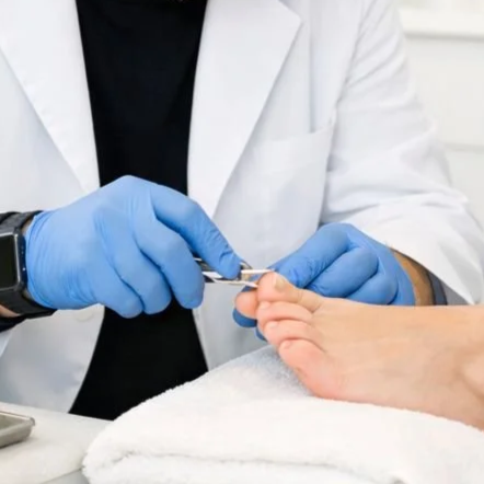 Modern house with wood and stone exterior on green rolling hills, snow-capped mountains in the background, under cloudy sky.