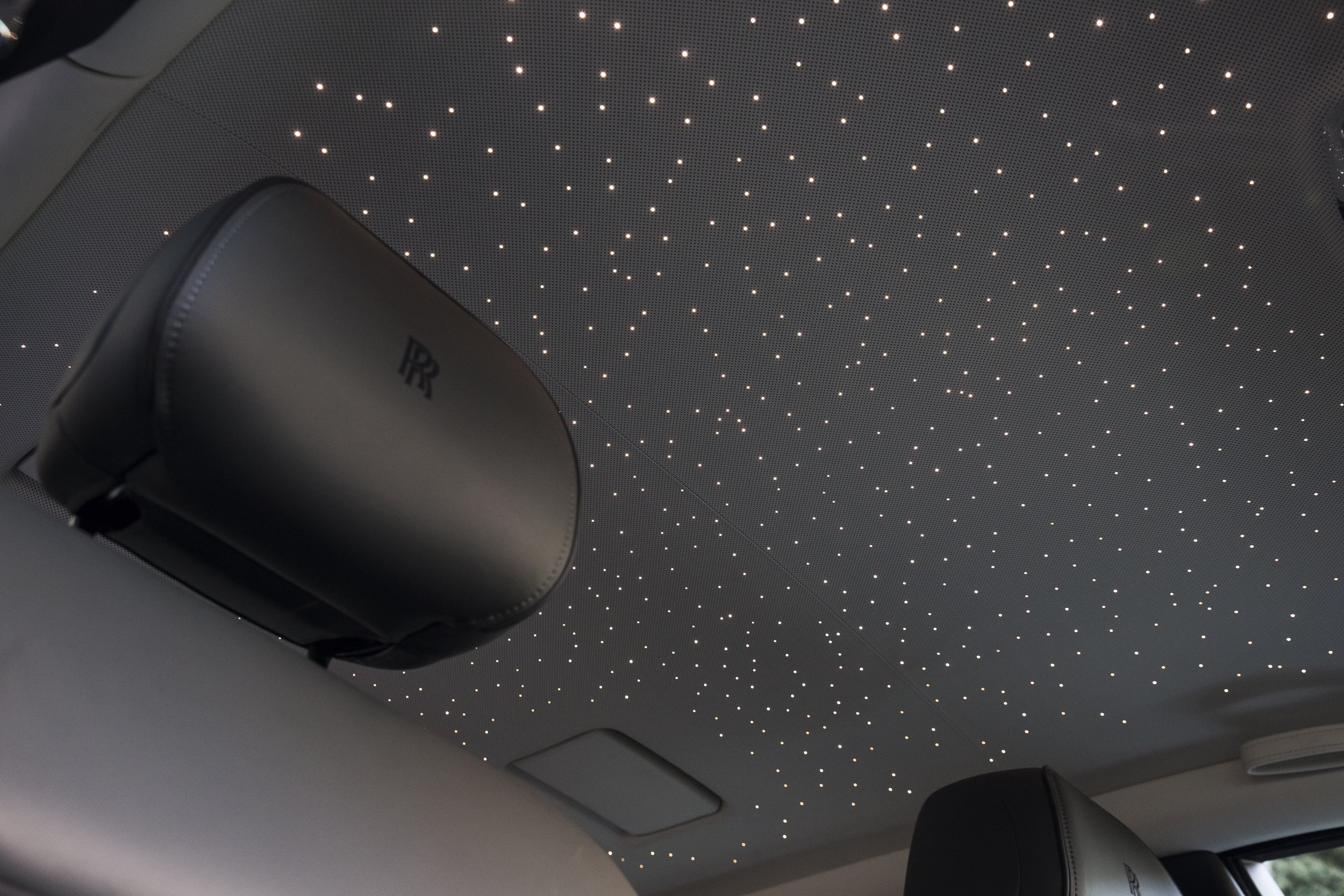 Luxurious car interior with starlight headliner and headrest logo.