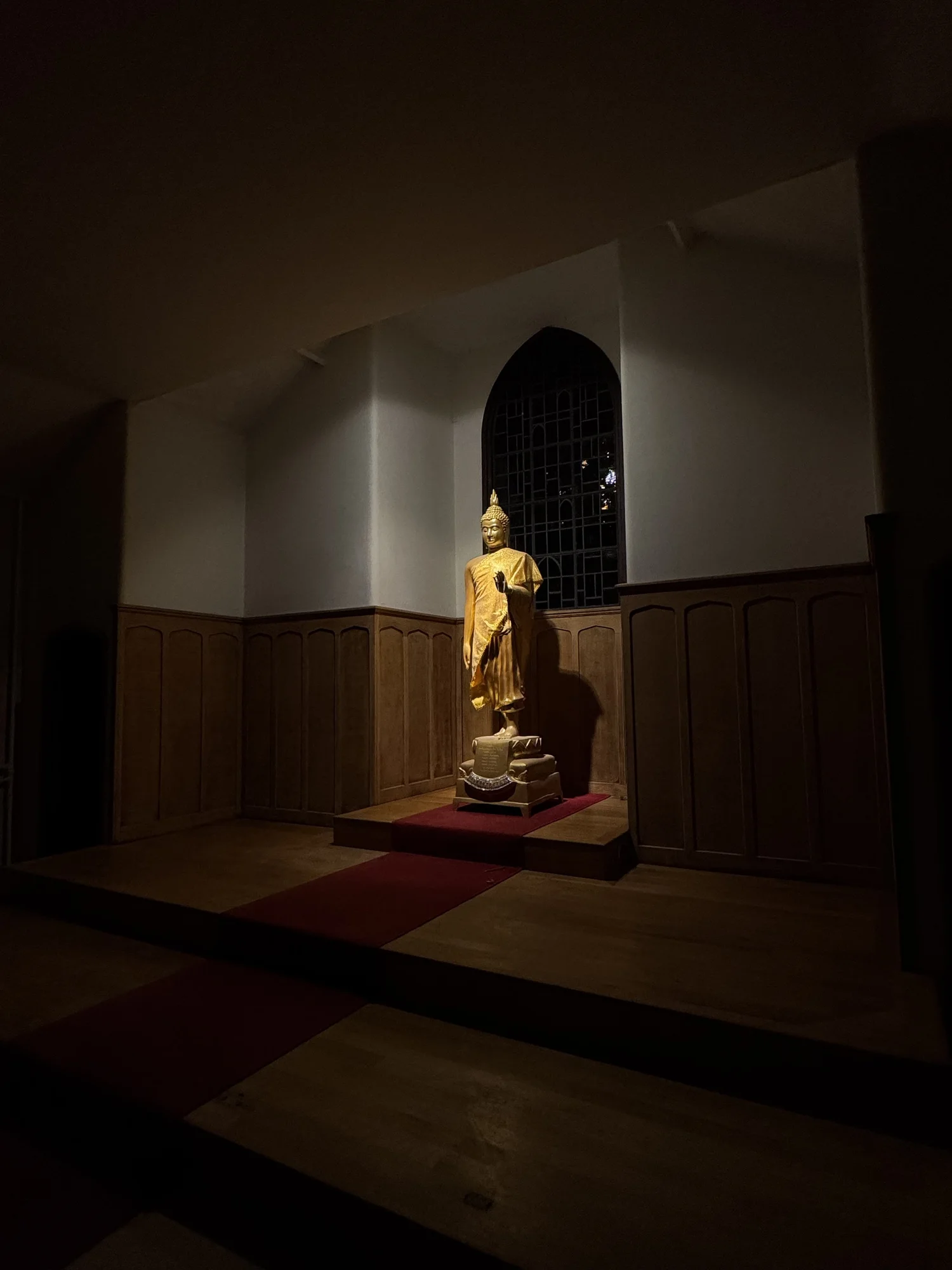 A golden Buddha statue illuminated in the shrine room at the Dhamma Centre, Colchester