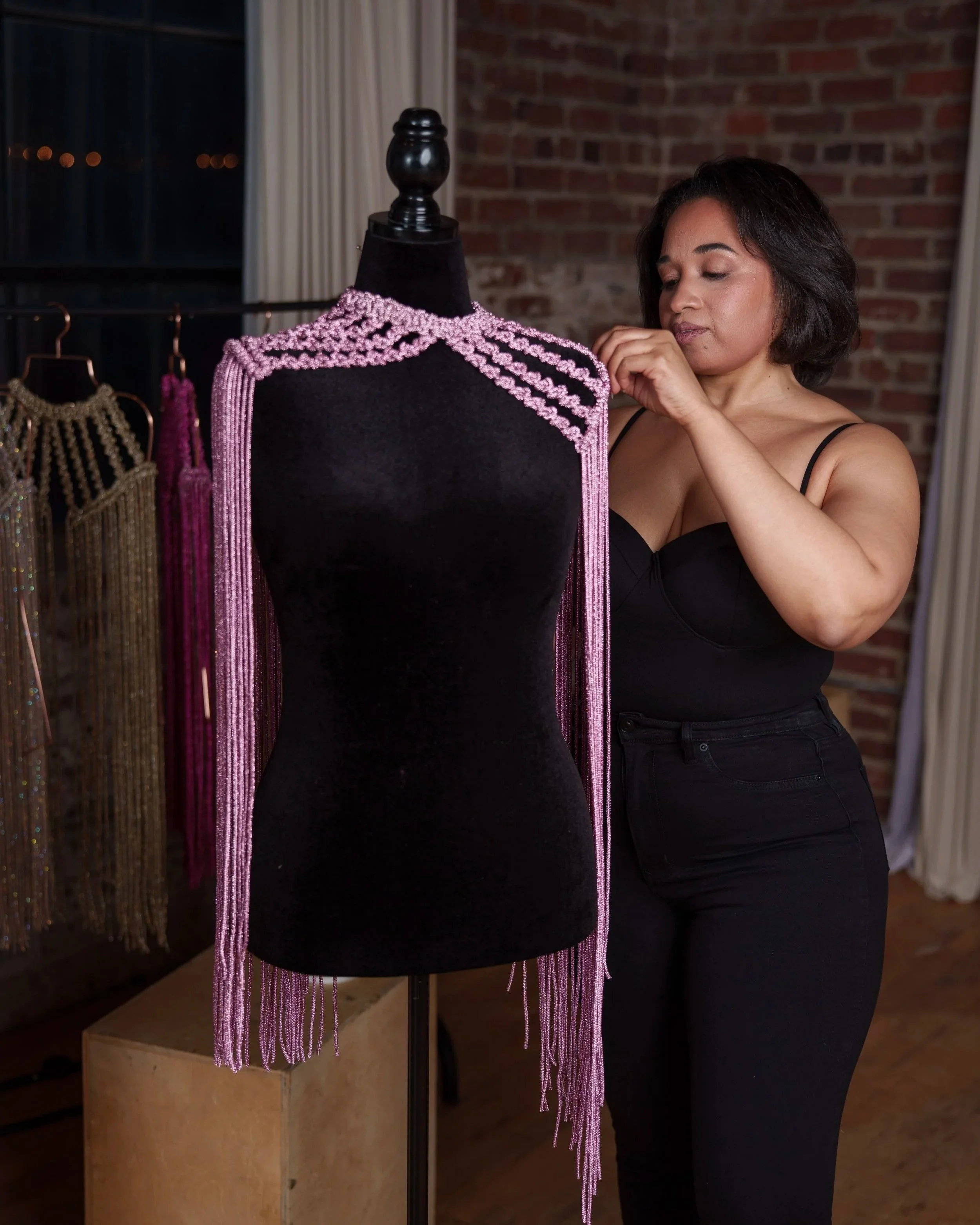 Macramé fringe choker displayed on a mannequin while being adjusted by a model in a studio