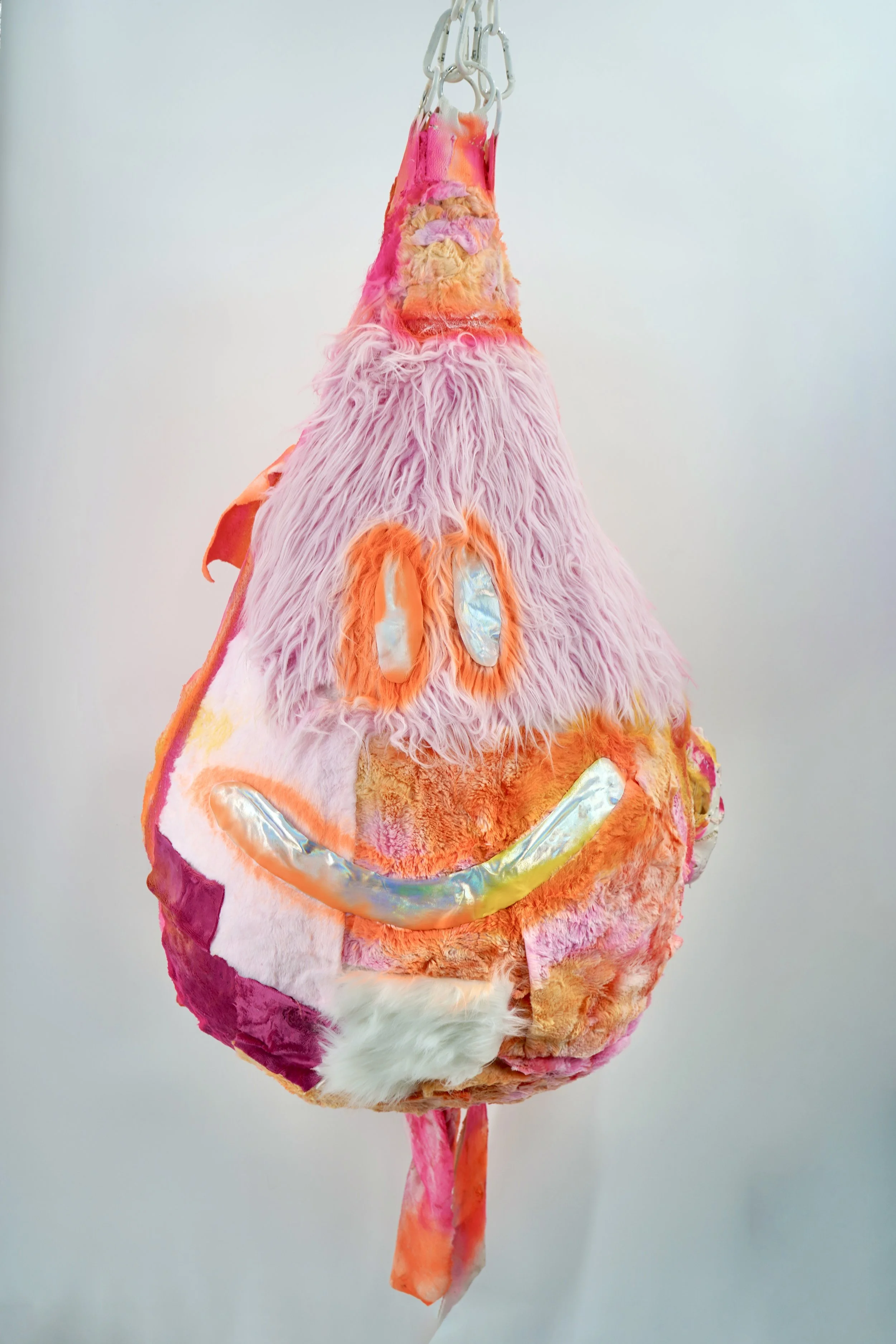 In The Recovering People Pleaser, artist Sophia Huang transforms a punching bag into a fragile, fabric-collaged vessel whose rupturing spray foam and paint reveal the moment when suppressed emotion breaks containment and becomes visible renewal.