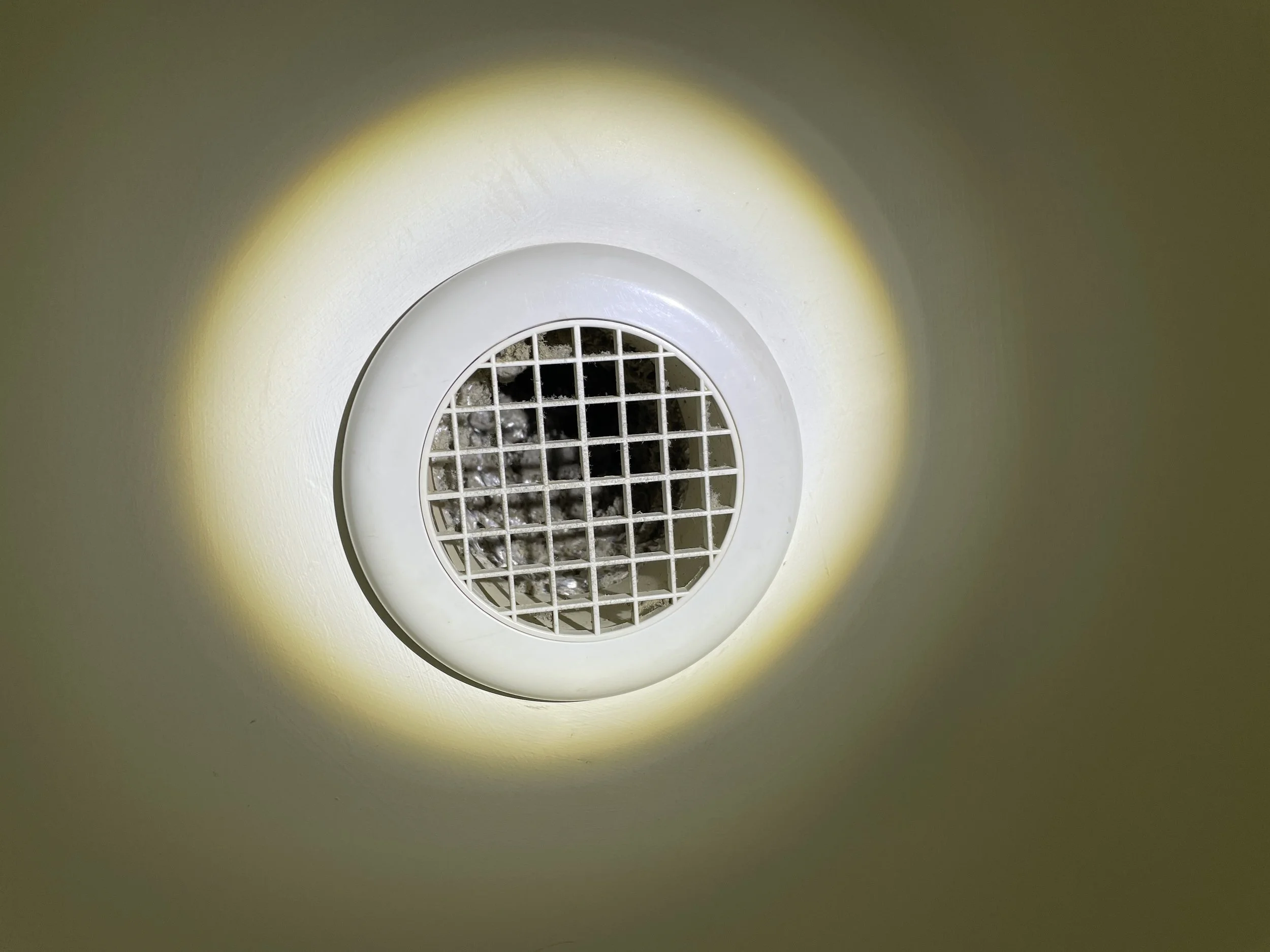 Bathroom extract grille blocked by dust, restricting airflow – root cause of condensation identified in compliance survey, Milton Keynes