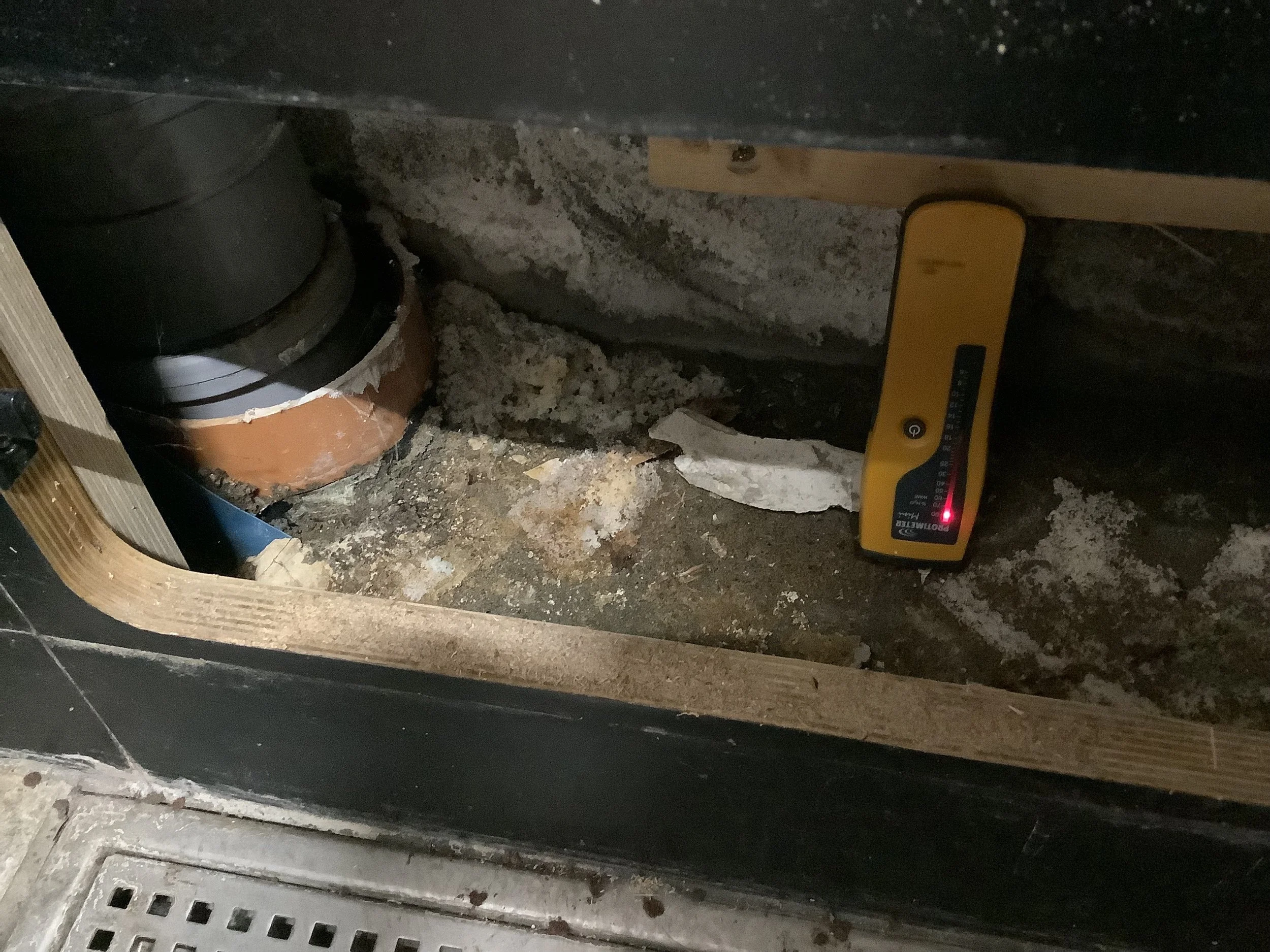 Moisture meter reading taken behind service boxing showing damp surface and salt deposits likely influencing conductivity – Durndell Building Surveyors, Milton Keynes.