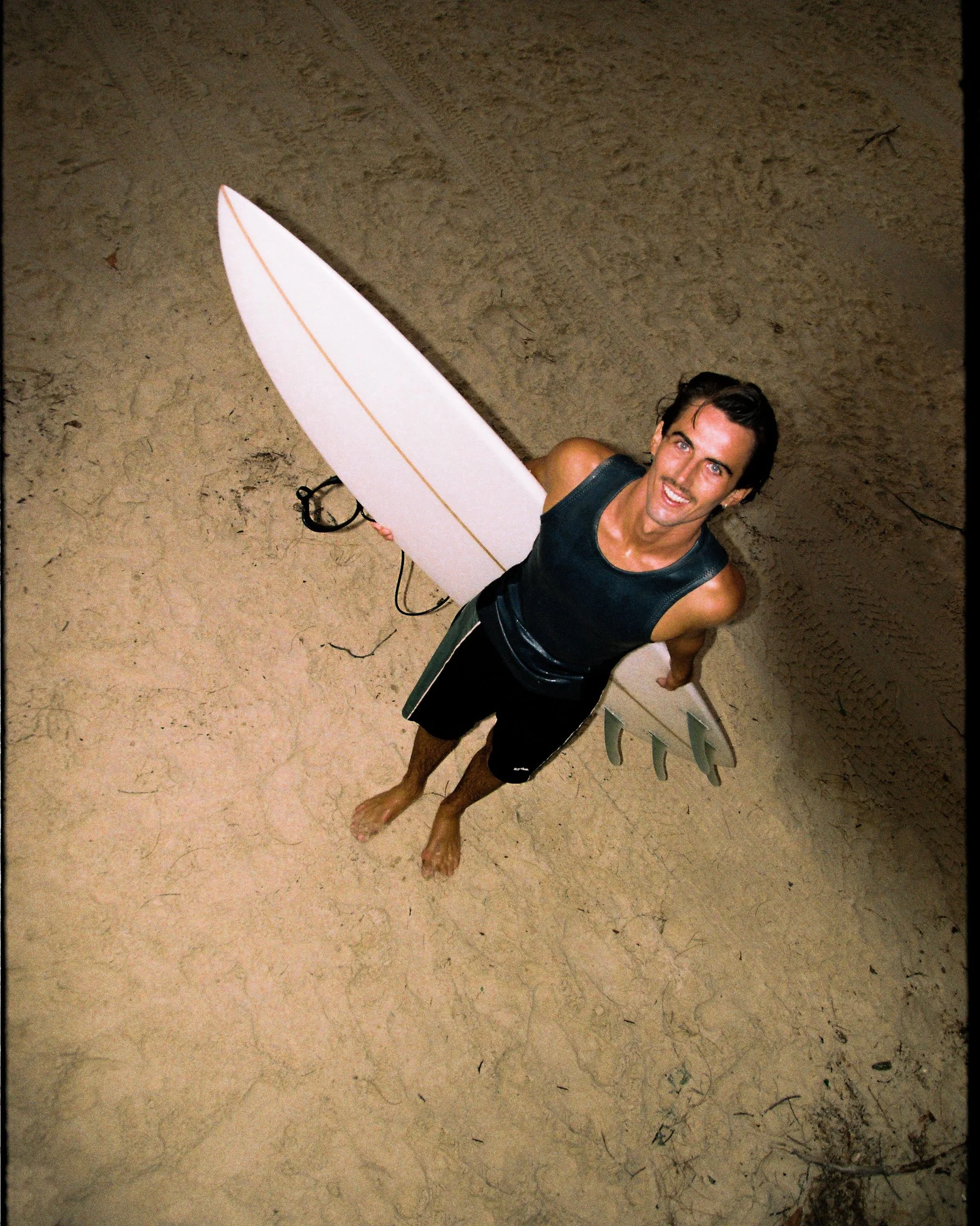 A surfer carrying a fish on the beach, photographed from above for the Dingley maker story.
